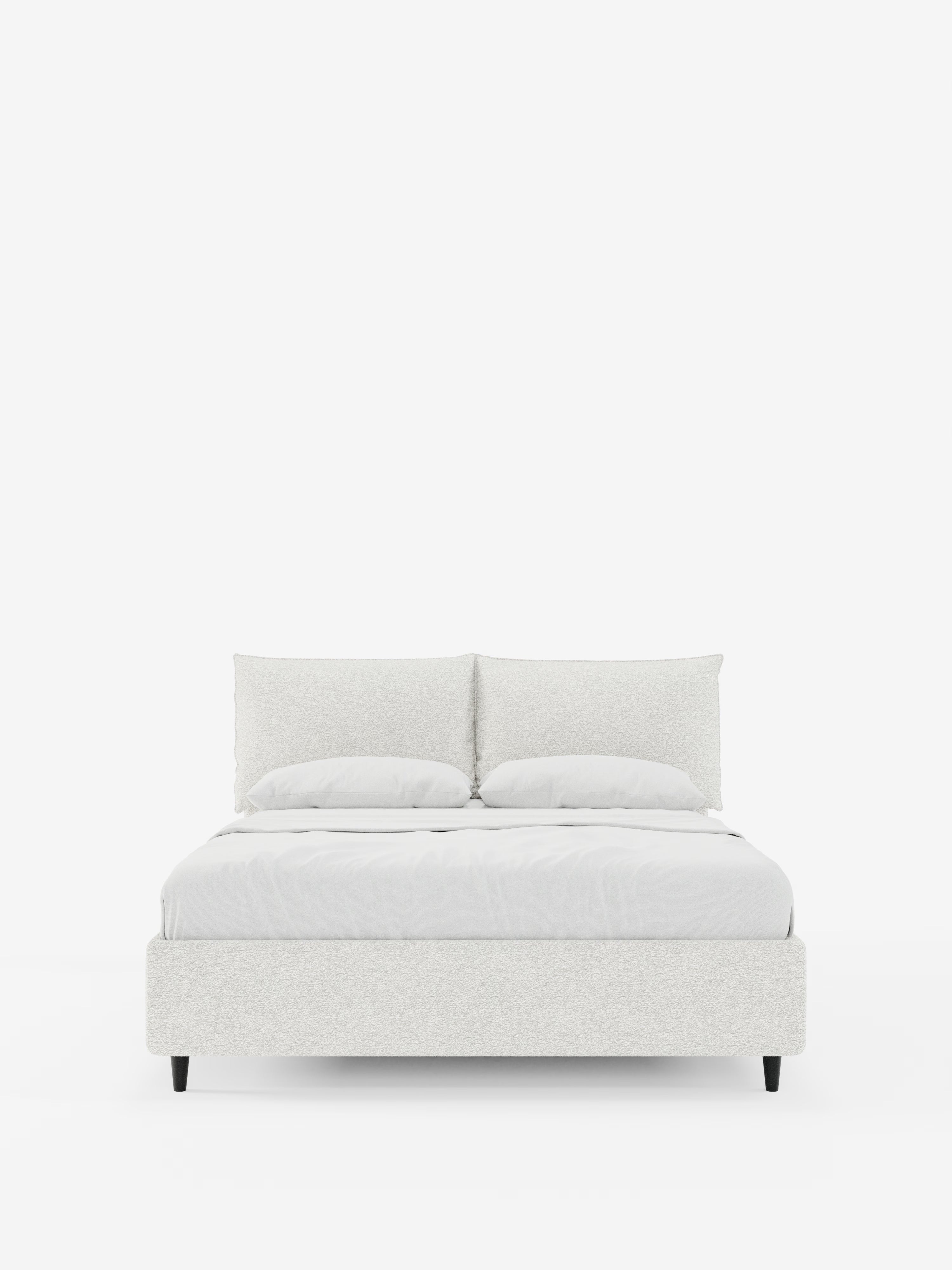 Un moderno letto imbottito ZAYRON di Letti.store, caratterizzato da una testata regolabile rivestita in tessuto e certificata Oeko-Tex®, due morbidi cuscini regolabili e biancheria da letto disposta con cura, poggia su corte gambe nere su uno sfondo bianco a tinta unita.