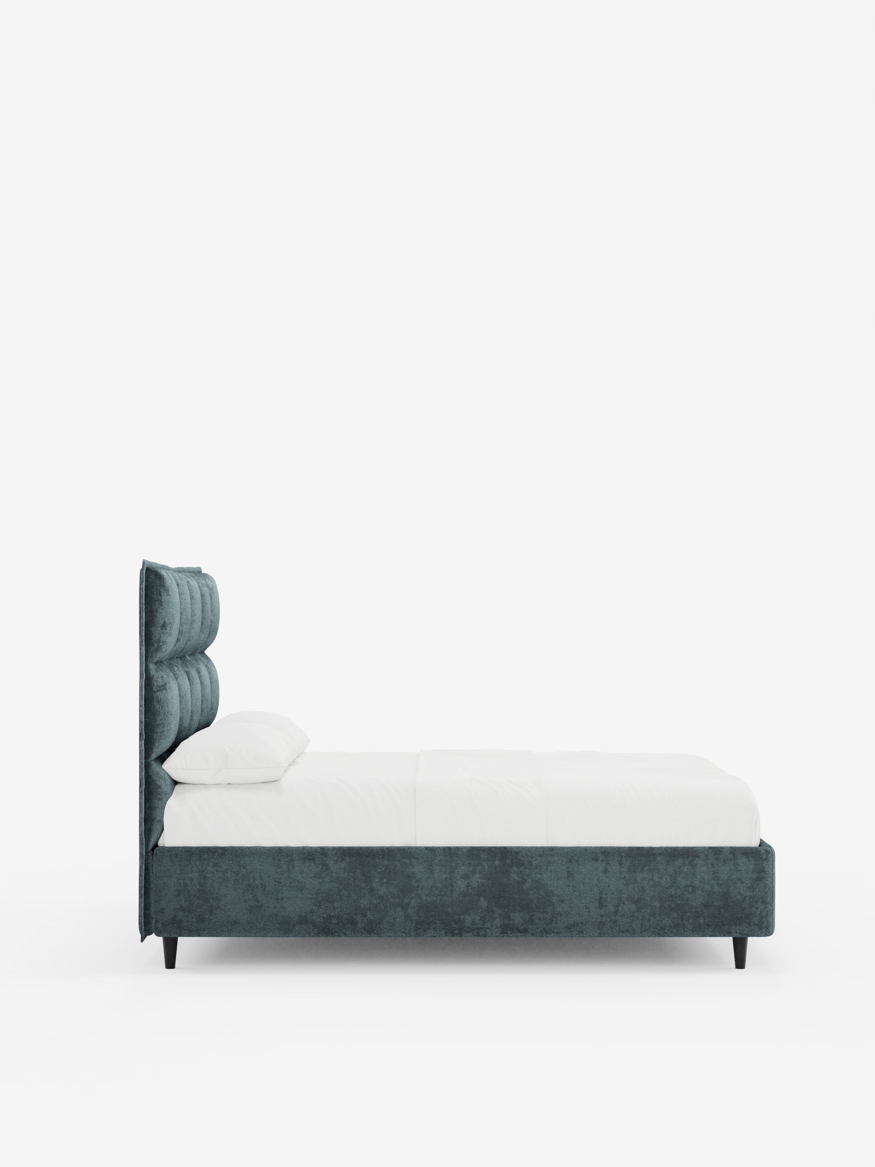 Vista laterale del letto imbottito AURO con contenitore e testiera alta capitonné in ciniglia Oeko-Tex® di Letti.store, caratterizzato da una morbida testiera color verde acqua con trapuntatura verticale ispirata al design capitonné. Il letto è rivestito con biancheria da letto bianca e fresca, con due cuscini, poggia su corte gambe nere e presenta una silhouette minimalista su uno sfondo bianco a tinta unita.