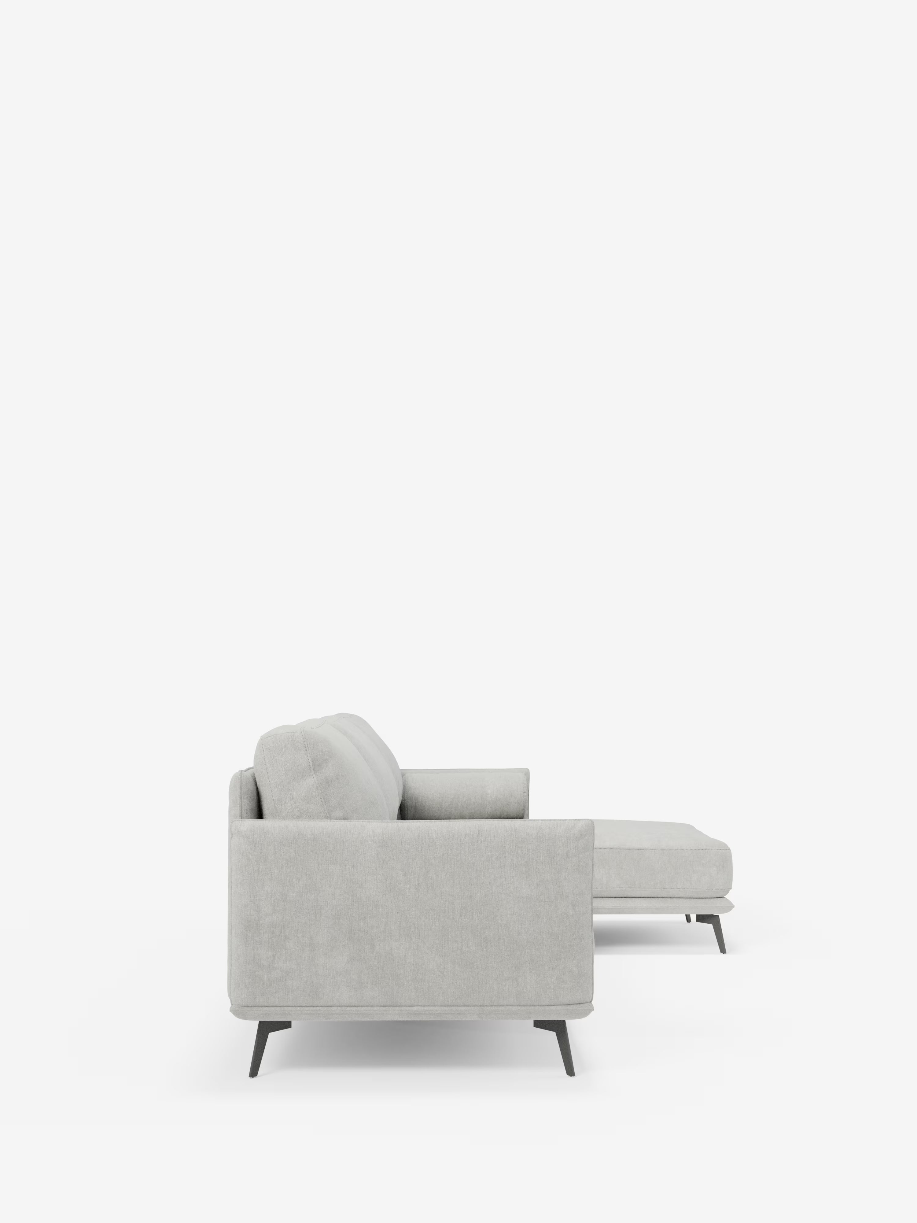 Vista laterale del divano moderno angolare con penisola “Basalto” di Divani.Store, presentato in grigio chiaro con chaise longue orientata a destra su uno sfondo bianco a tinta unita. Questo divano contemporaneo presenta braccioli squadrati, morbidi cuscini in piuma rivestiti in tessuto T31 antimacchia e gambe angolari in metallo nero, per un'estetica minimalista e moderna.