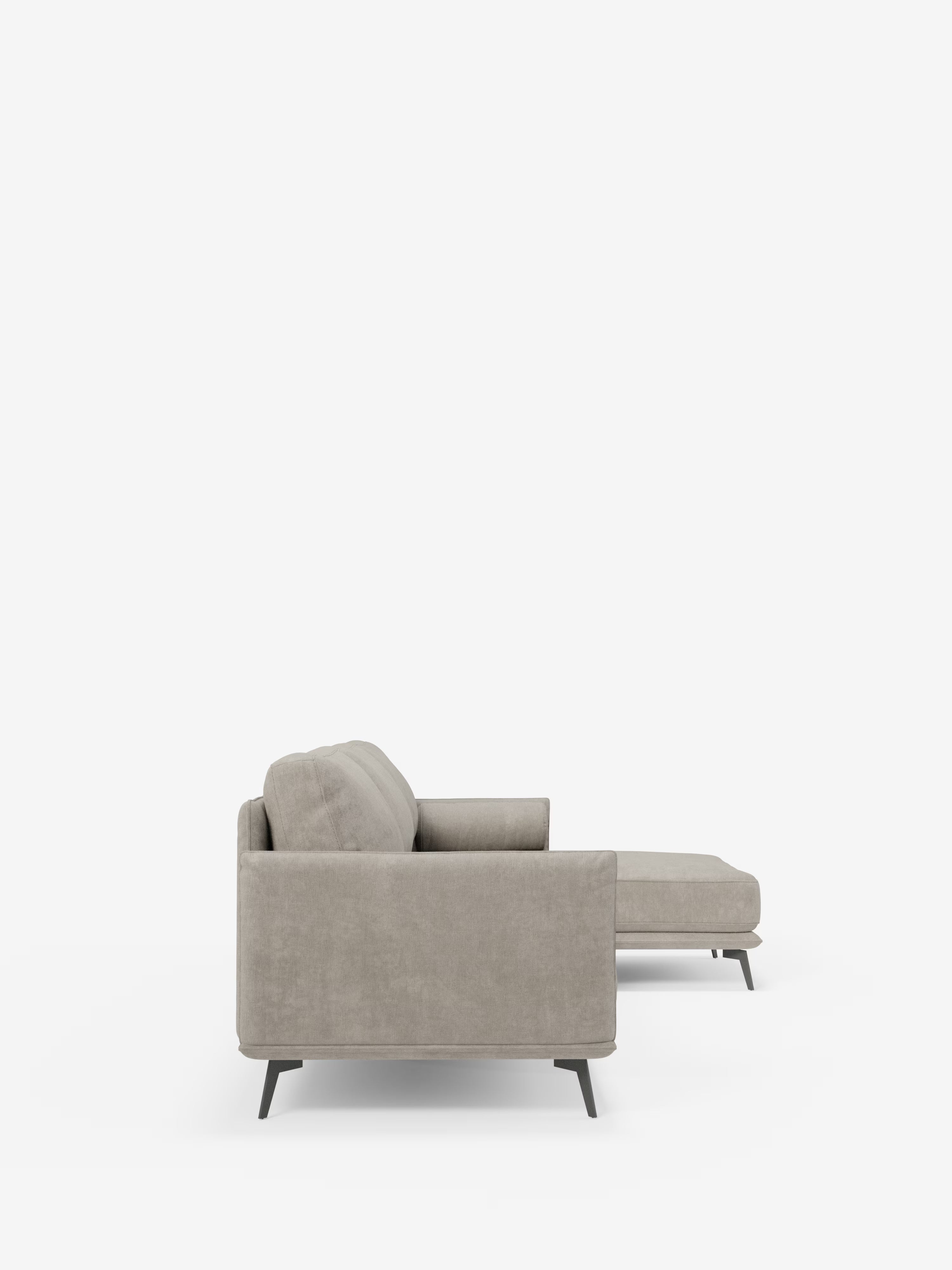 Vista laterale del divano moderno angolare con penisola "Basalto" di Divani.Store, rivestito in tessuto T31 grigio chiaro, antimacchia, con chaise longue sulla destra. Questo divano Made in Italy presenta linee pulite, braccioli squadrati, cuscini in piuma e una base in metallo con gambe scure e angolate. È ripreso su uno sfondo bianco a tinta unita per mantenere l’attenzione sul mobile stesso.