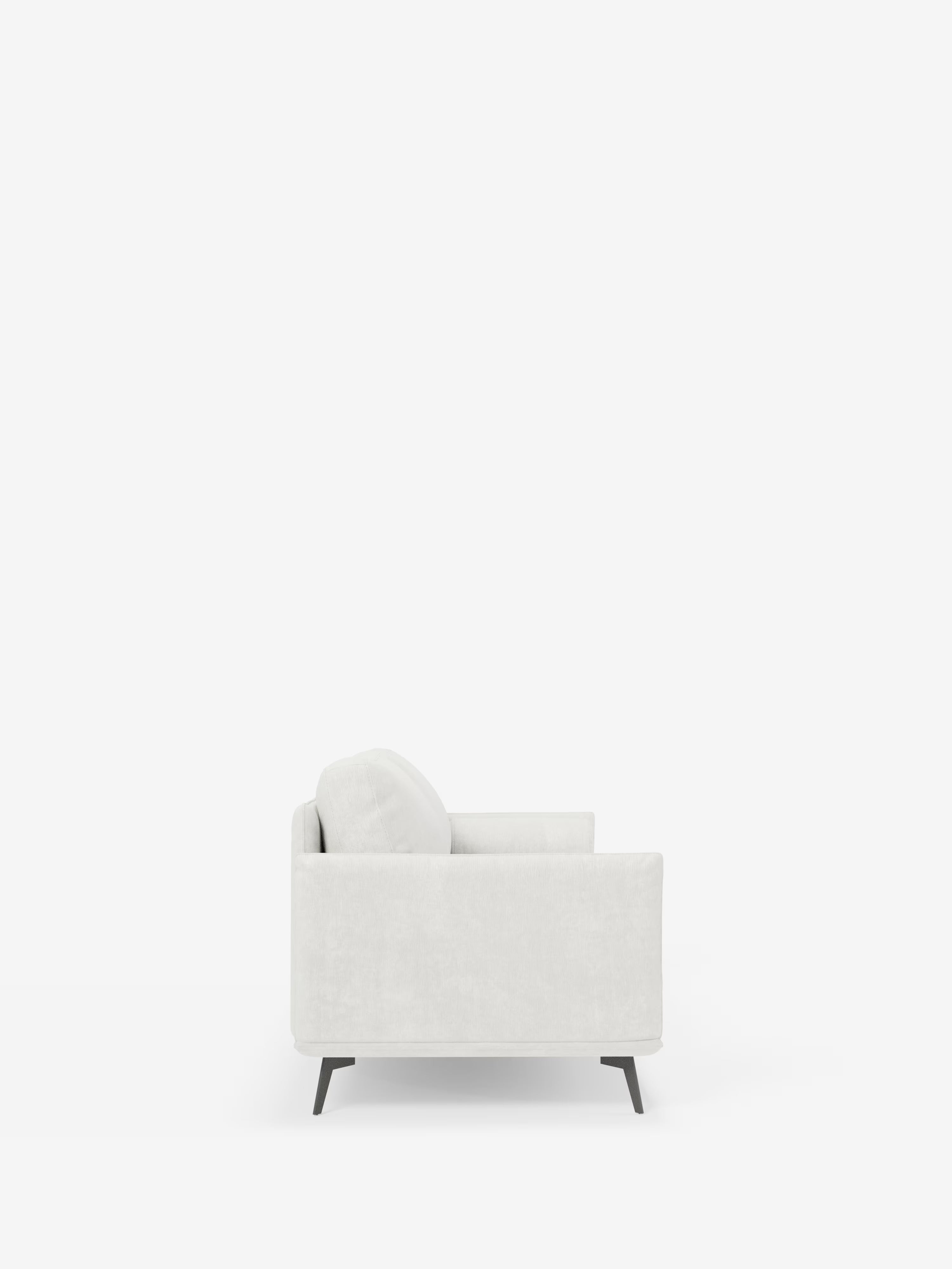 Vista laterale del divano lineare Basalto a 2 o 3 posti di Divani.Store, qui presentato come un moderno divano imbottito bianco con un unico cuscino di seduta e uno schienale. Il design è caratterizzato da sottili gambe angolate in metallo nero ed è presentato su uno sfondo bianco a tinta unita per un'elegante estetica da divano minimalista. Realizzato in tessuto smacchiabile T31, questo divano unisce praticità e stile contemporaneo.