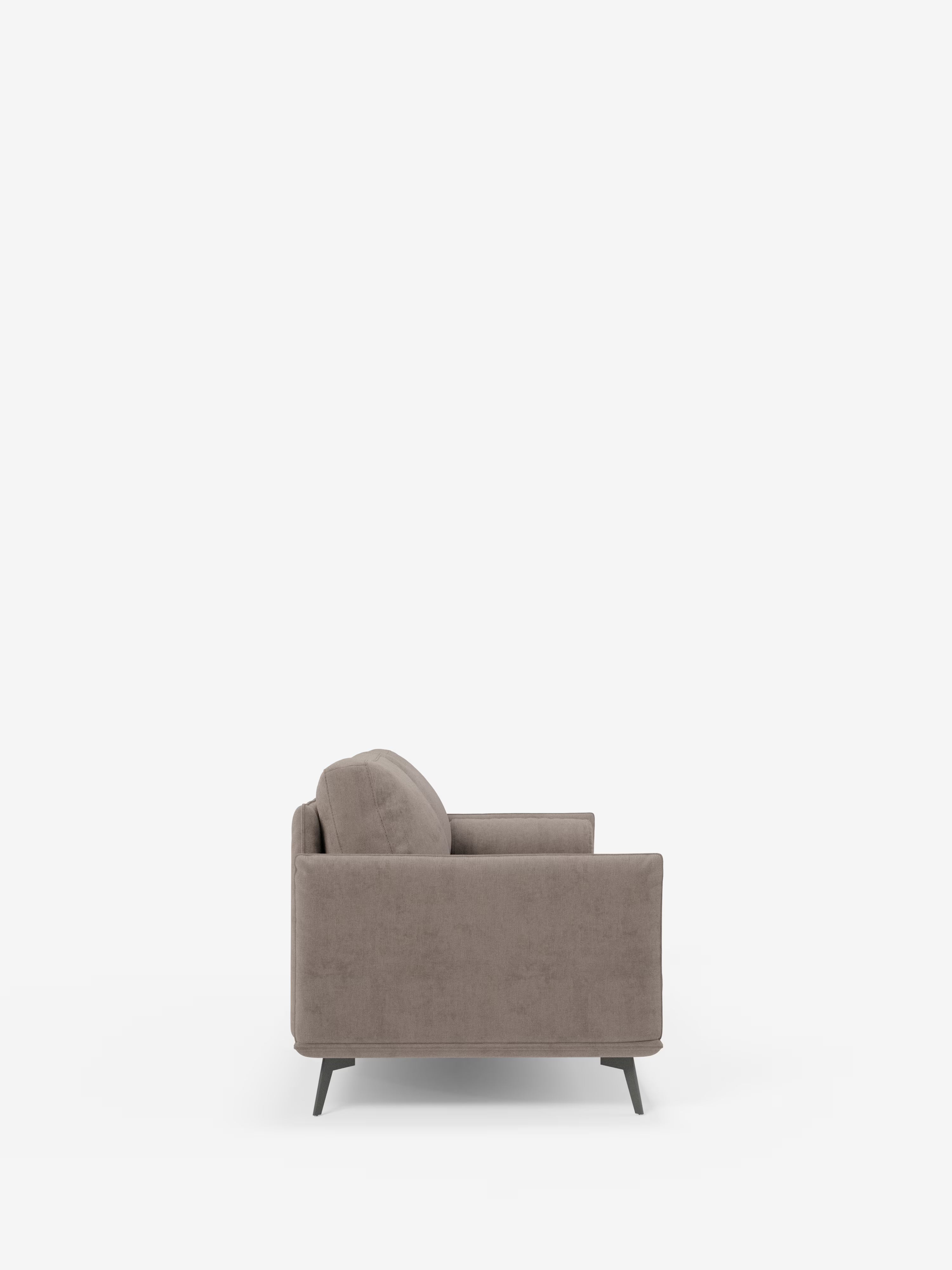 Un moderno divano lineare Basalto color taupe a 2 o 3 posti con seduta unica e base in metallo, rivestito in tessuto antimacchia T31 di Divani.Store, è raffigurato in una vista laterale su uno sfondo bianco a tinta unita. Ispirato al design minimalista, questo divano presenta schienale, seduta e braccioli imbottiti, con gambe corte e angolate in finitura metallica scura. Il rivestimento liscio e antimacchia esalta il fascino accogliente delle sue linee pulite.