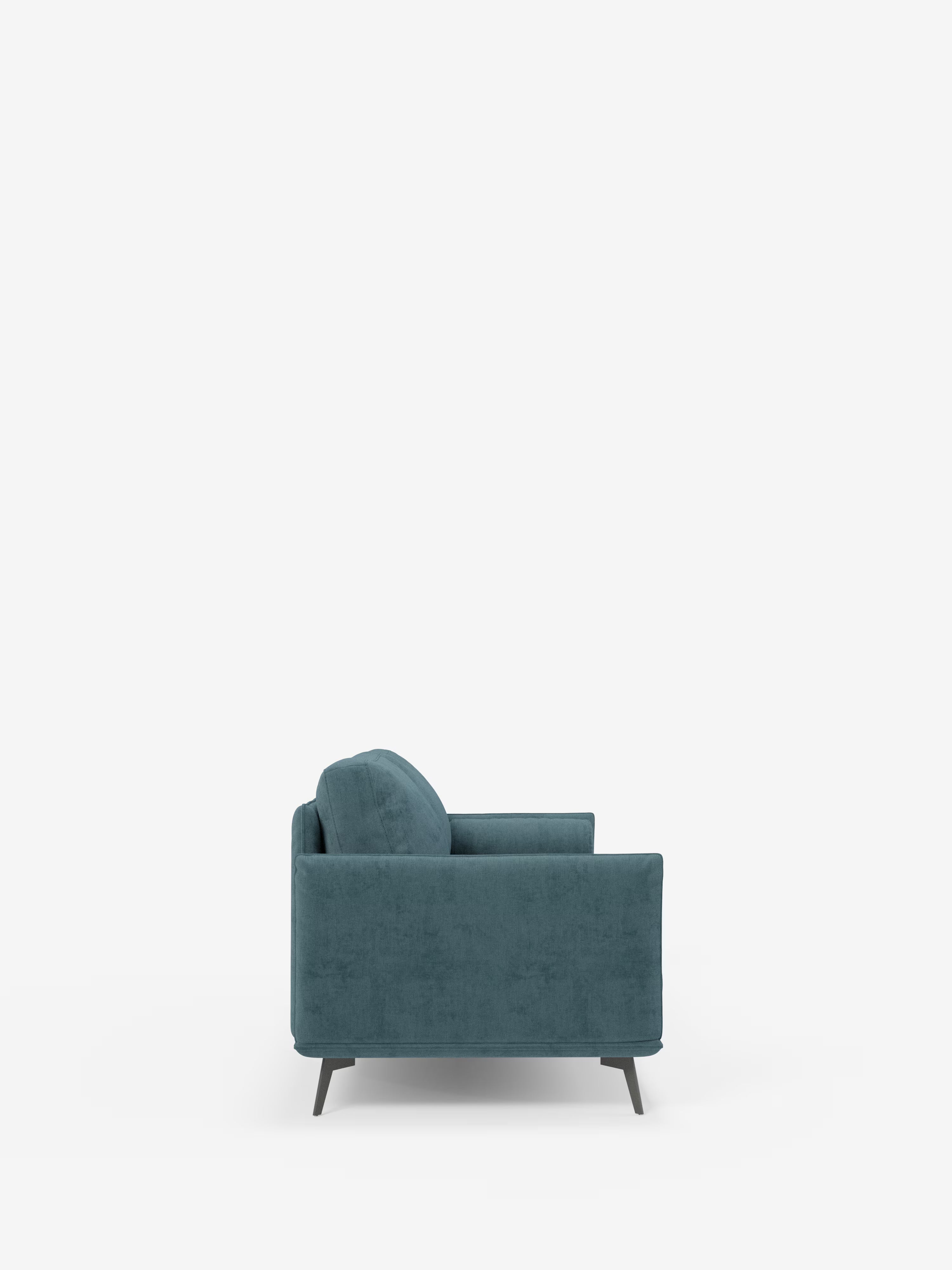 Una vista laterale del divano lineare Basalto a 2 o 3 posti con seduta unica e base in metallo, rivestito in tessuto smacchiabile T31 di Divani.Store, ne mette in risalto il moderno rivestimento color verde acqua, le gambe affusolate scure e la robusta base in metallo. I braccioli e lo schienale imbottiti ne sottolineano il comfort, mentre la silhouette slanciata del divano risalta su uno sfondo bianco a tinta unita, mettendo in risalto il suo design minimalista.