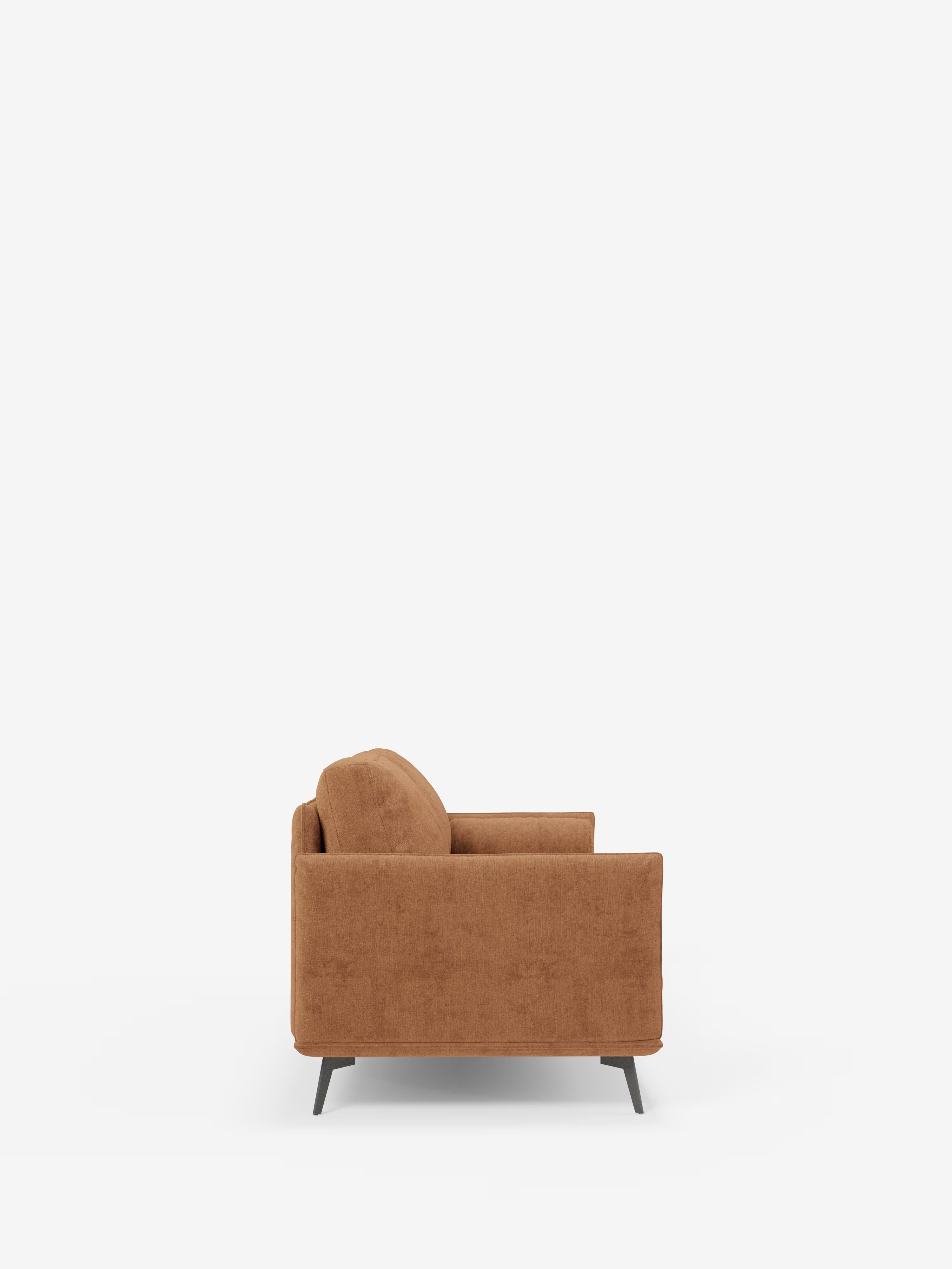 Una vista laterale del Basalto Divano lineare a 2 o 3 posti con seduta unica e base in metallo, rivestito in tessuto antimacchia T31 di Divani.Store, ne mette in risalto la silhouette moderna, il rivestimento in tessuto marrone antimacchia, l’imbottitura generosa e le gambe in metallo nero. Le linee pulite e il design minimalista — che richiamano un divano minimalista — risaltano sullo sfondo bianco.
