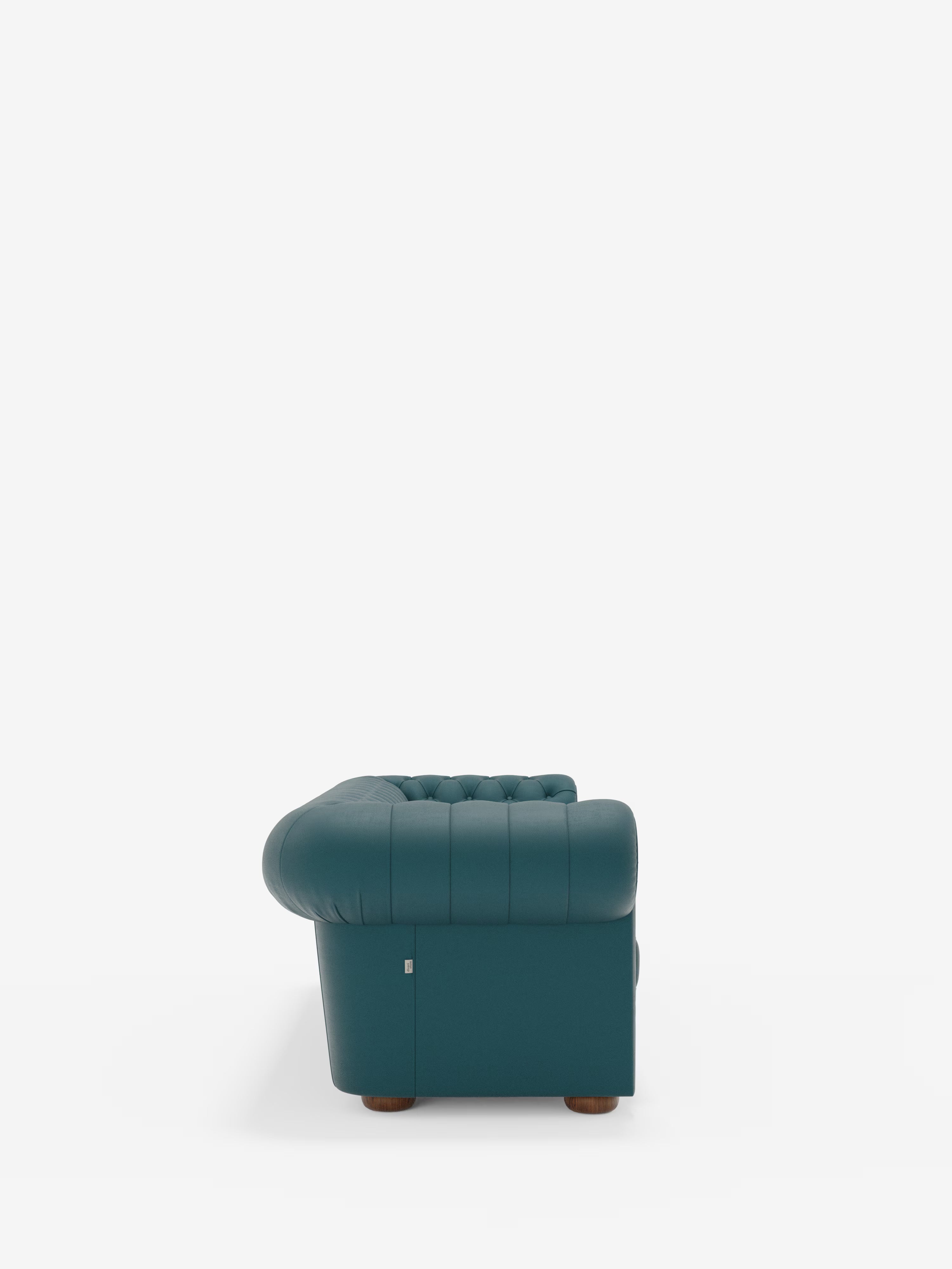 Vista laterale del divano Chester 4 Posti 3 sedute in Vera Pelle – Chesterfield Capitonné Artigianale di Divani.Store, un divano imbottito color verde acqua con rivestimento capitonné realizzato artigianalmente, caratterizzato da braccioli e schienale arrotondati, poggiato su gambe corte in legno su uno sfondo bianco a tinta unita.