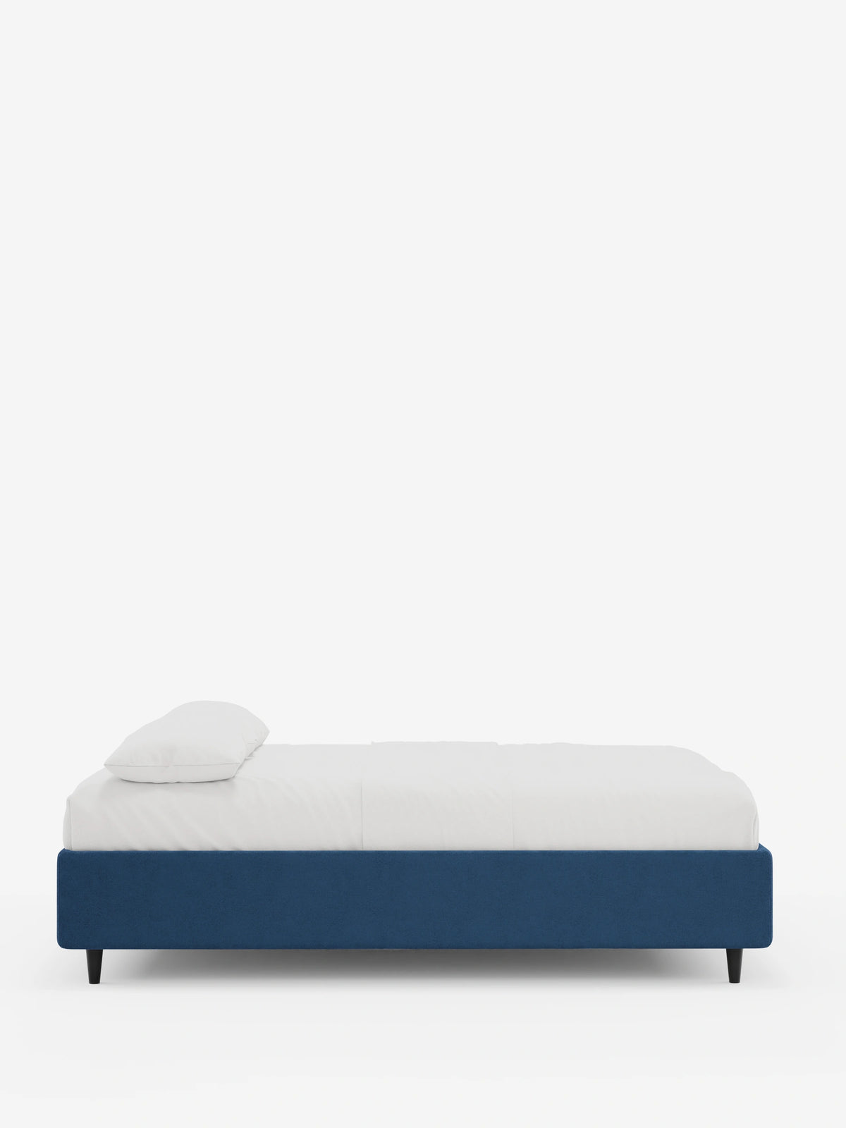 Il letto sommier imbottito ERON con contenitore in tessuto impermeabile certificato Oeko-Tex è un letto imbottito di colore blu intenso, con lenzuola bianche e un cuscino rettangolare singolo, sostenuto da quattro gambe affusolate, sottili e di colore scuro.