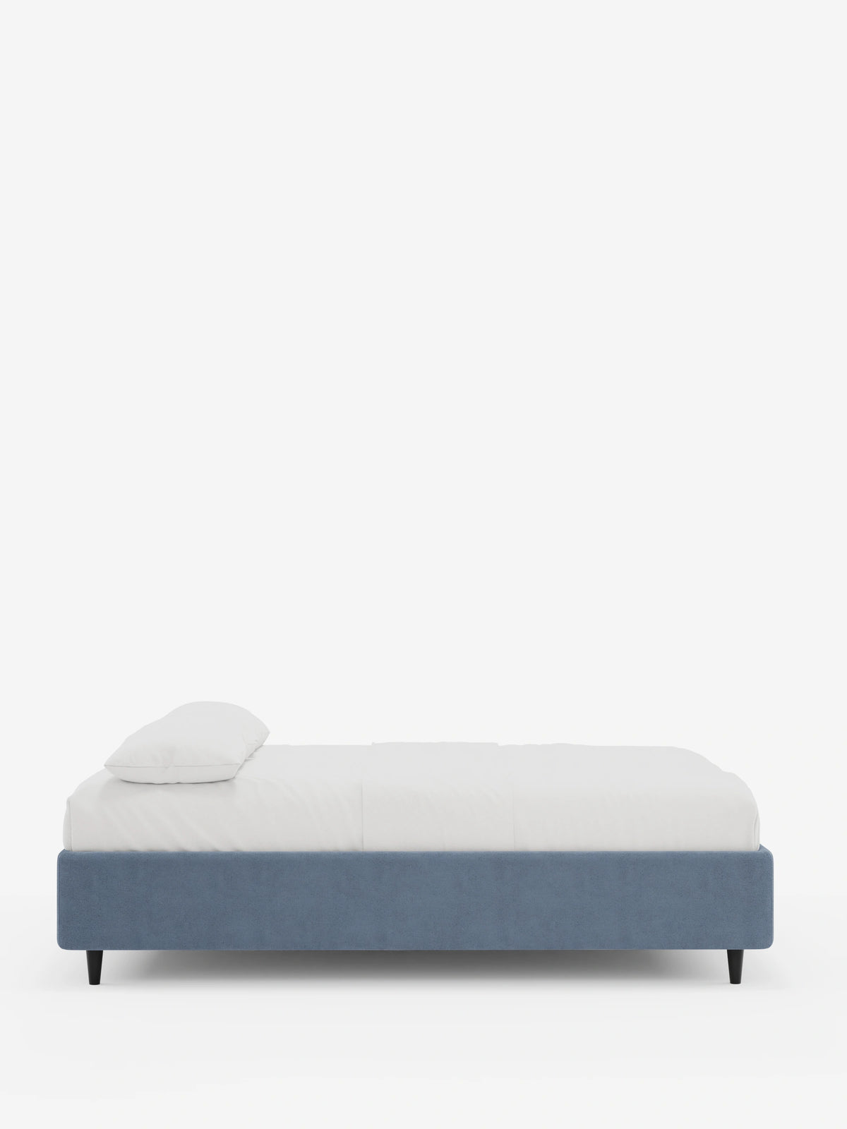 Una vista laterale del letto sommier imbottito ERON con vano contenitore in tessuto impermeabile certificato Oeko-Tex, caratterizzato da una base imbottita blu, gambe corte scure, un materasso bianco e un cuscino bianco su uno sfondo chiaro a tinta unita.