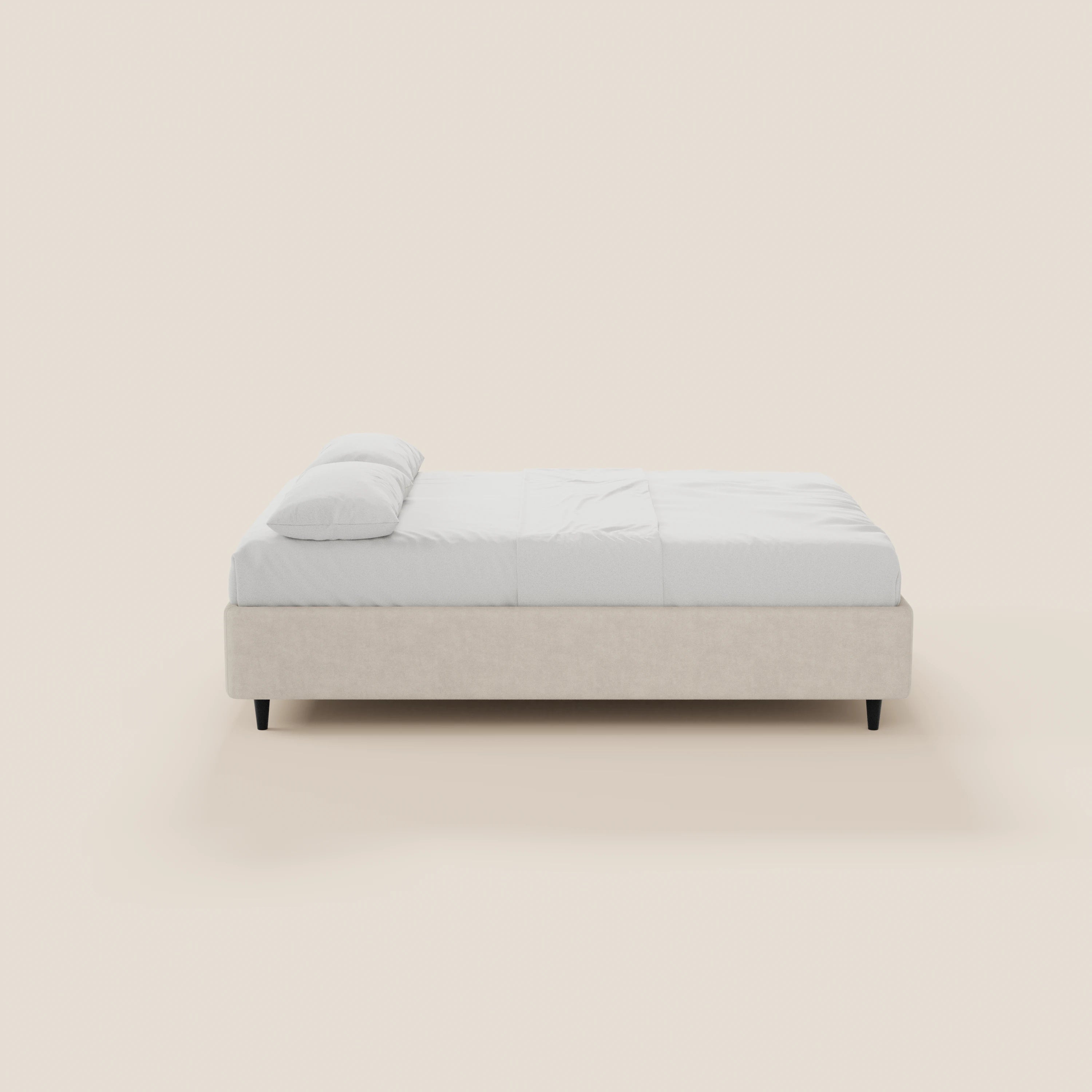 Il letto sommier imbottito ERON di Letti.store presenta una struttura in tessuto beige impermeabile certificato Oeko-Tex, biancheria da letto bianca, un cuscino singolo, gambe corte scure e un design moderno e minimalista, raffigurato di profilo su uno sfondo beige chiaro.