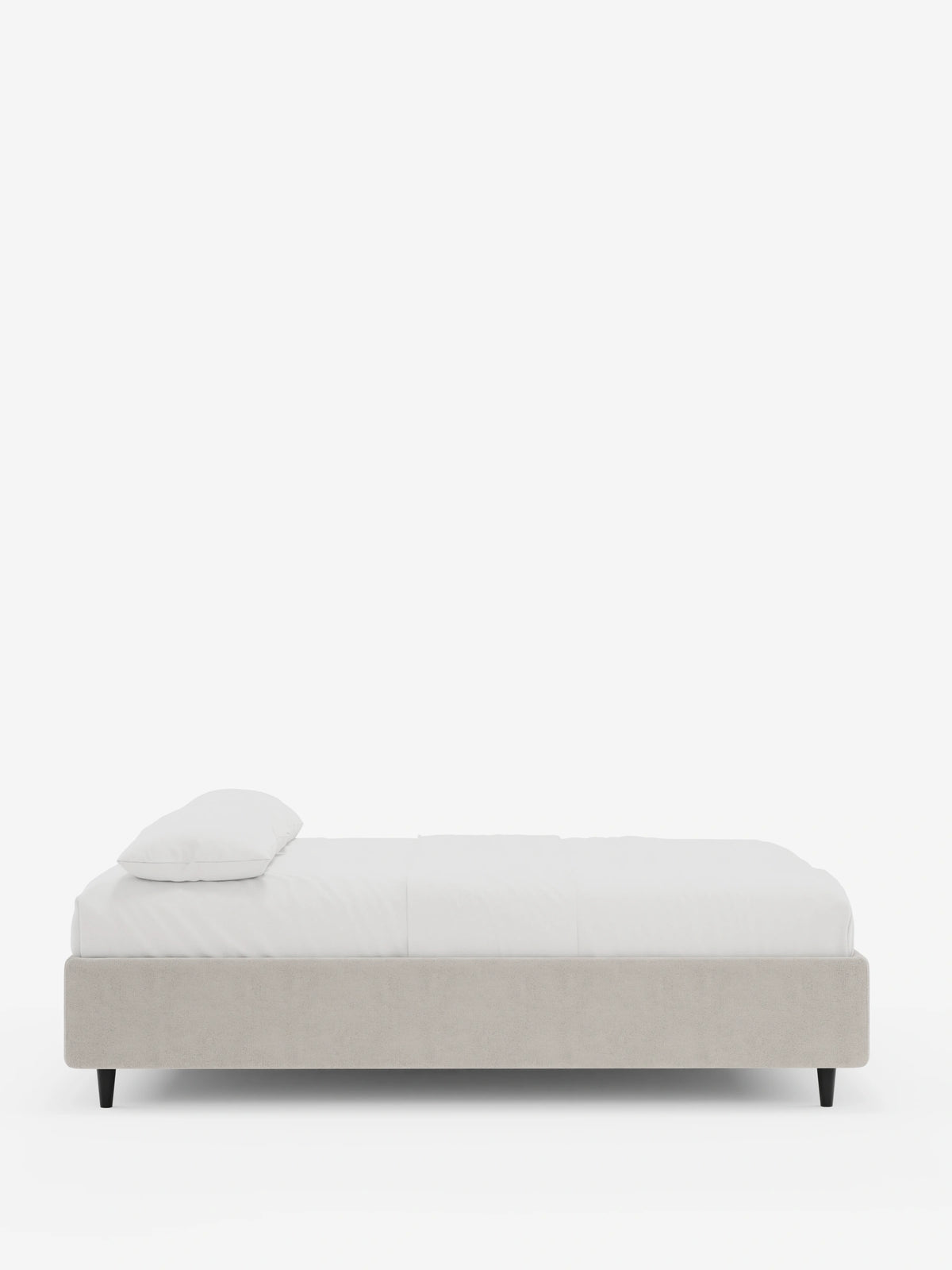Vista laterale di un letto sommier imbottito ERON con contenitore, rivestito in tessuto impermeabile certificato Oeko-Tex color beige, con un materasso bianco, un cuscino bianco e gambe basse affusolate nere su uno sfondo bianco a tinta unita.