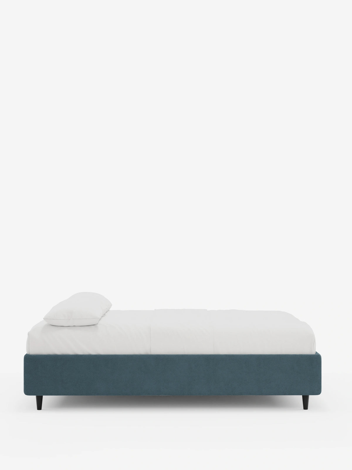 Vista laterale di un letto sommier imbottito ERON con contenitore, rivestito in tessuto impermeabile certificato Oeko-Tex di colore blu tenue, caratterizzato da gambe corte scure, un lenzuolo bianco e un unico cuscino bianco su uno sfondo bianco sporco.