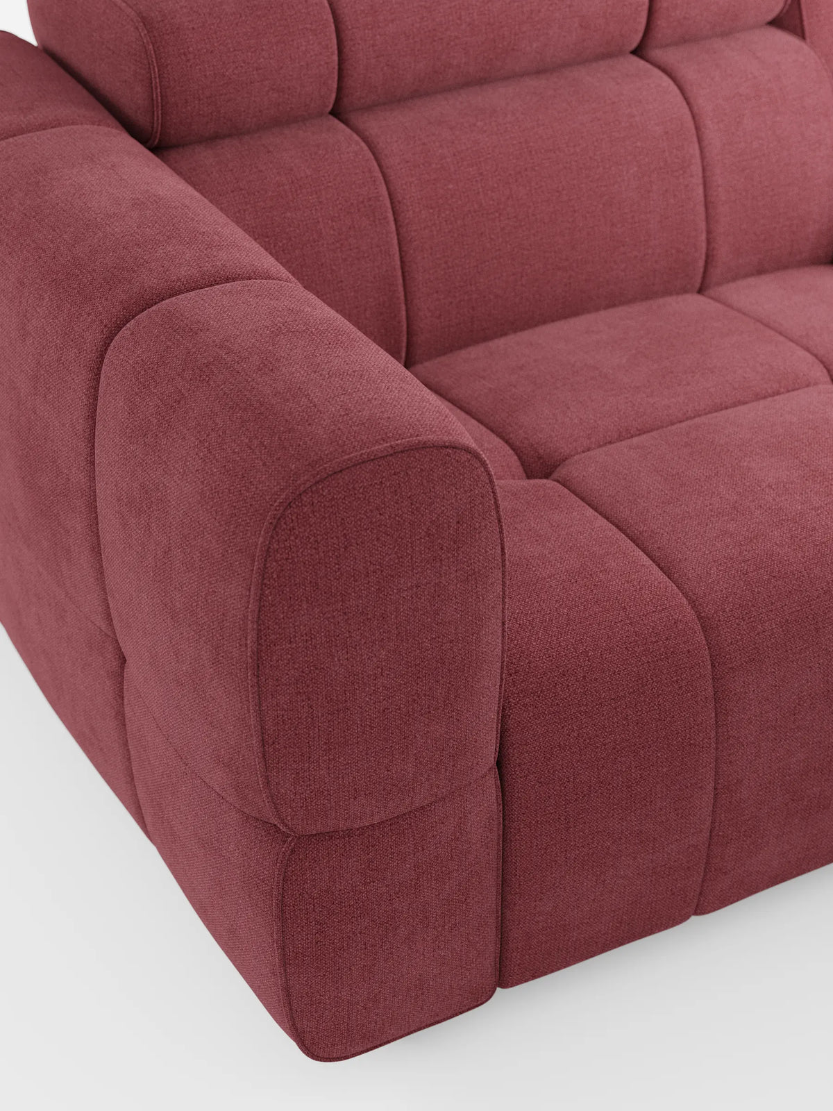 Un primo piano di un divano modulare Giotto a 3 posti, rivestito in tessuto rosso intenso, caratterizzato da cuscini con cuciture quadrate, braccioli arrotondati e poggiatesta regolabili, su uno sfondo chiaro e semplice, che ne esalta il design contemporaneo.