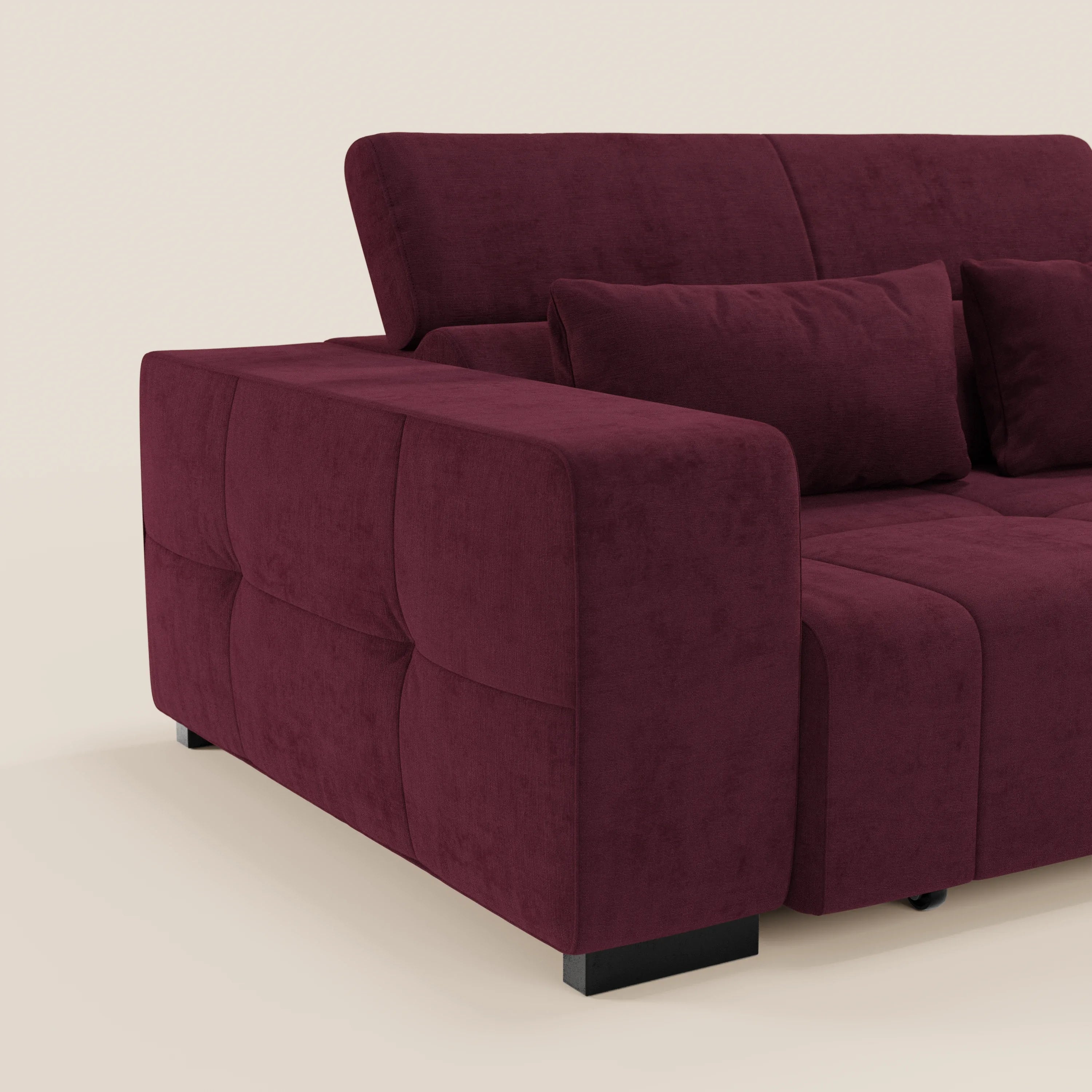 Monarch di Divani.Store è un moderno divano angolare bordeaux intenso con chaise, tessuto smacchiabile T31, poggiatesta reclinabili, estensione elettrica della seduta Relax, ampi braccioli imbottiti e un set di cuscini coordinati su uno sfondo beige chiaro.
