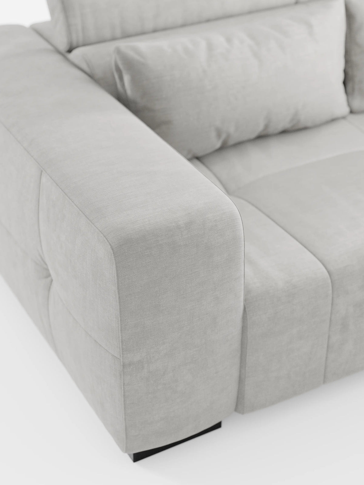 Un primo piano del divano Monarch con funzione relax elettrica per l'allungamento delle sedute e poggiatesta reclinabile di Divani.Modello rivestito in morbido tessuto T31 grigio chiaro, resistente alle macchie, con cuscini soffici e ampi braccioli, che ne esaltano la texture liscia e le cuciture minimaliste in stile italiano contemporaneo, su uno sfondo bianco.