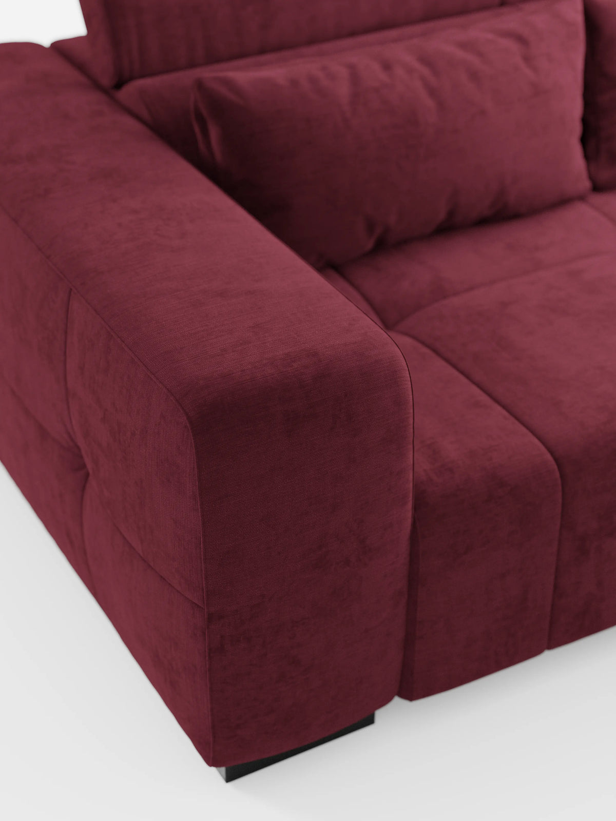 Un primo piano del divano Monarch con funzione relax elettrica per l’allungamento delle sedute e poggiatesta reclinabile, realizzato in morbido tessuto lavabile T31 di Divani.Store. L'immagine mette in risalto l'ampio e morbido bracciolo, la seduta trapuntata e un cuscino dello schienale abbinato. Dotato di un poggiatesta reclinabile per un comfort ancora maggiore, questo moderno divano rosso intenso poggia su brevi gambe nere su uno sfondo bianco, creando un look pulito ed elegante.