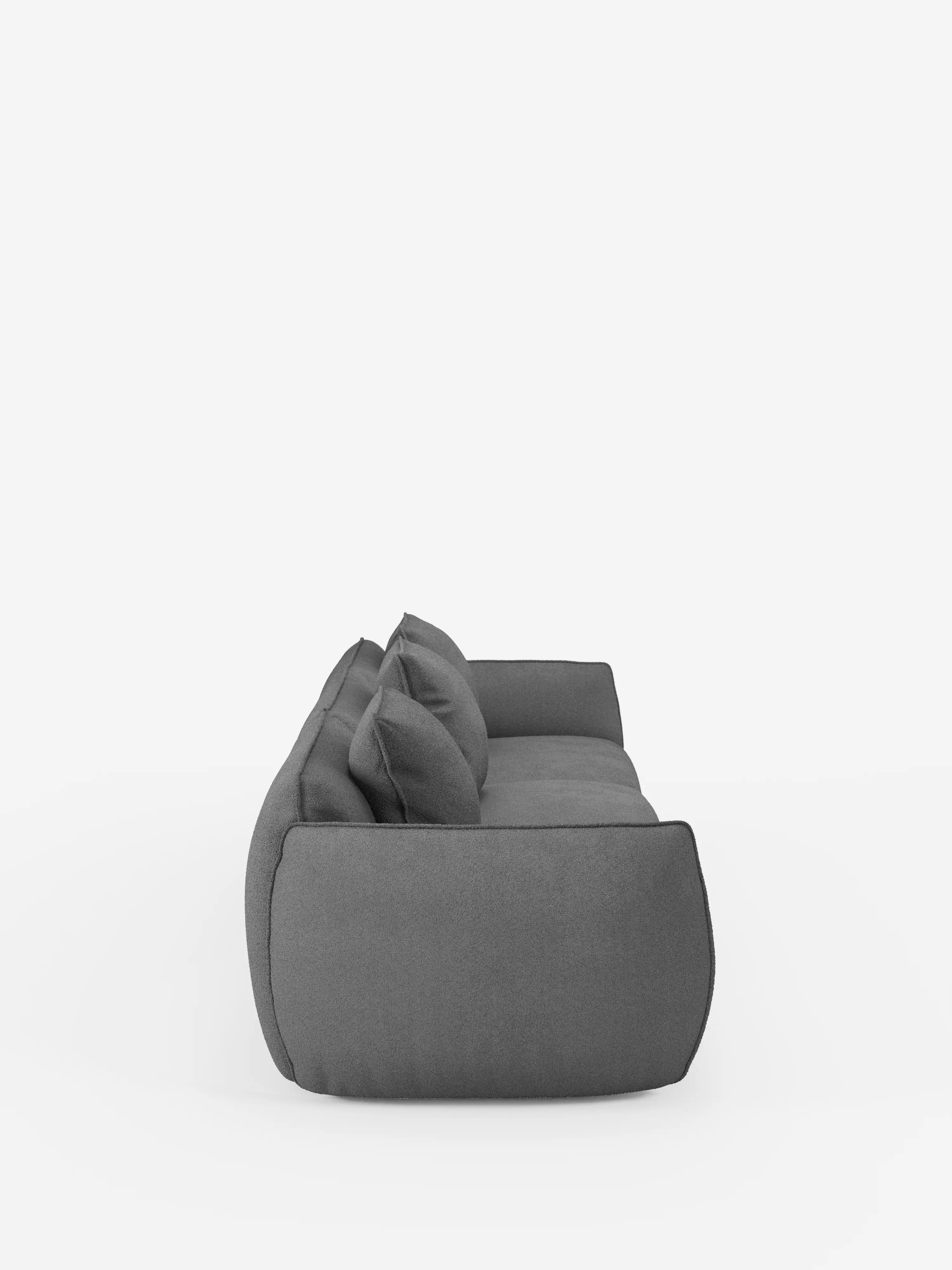 Vista laterale del divano modulare a 3 posti Nimbus, realizzabile in morbido tessuto lavabile effetto cotone T33 di Divani.Store, caratterizzato da un tessuto lavabile grigio scuro effetto cotone, due cuscini dello schienale e bordi delicatamente arrotondati. Su uno sfondo bianco a tinta unita, il divano emana un comfort avvolgente e mette in risalto un design minimalista e contemporaneo.