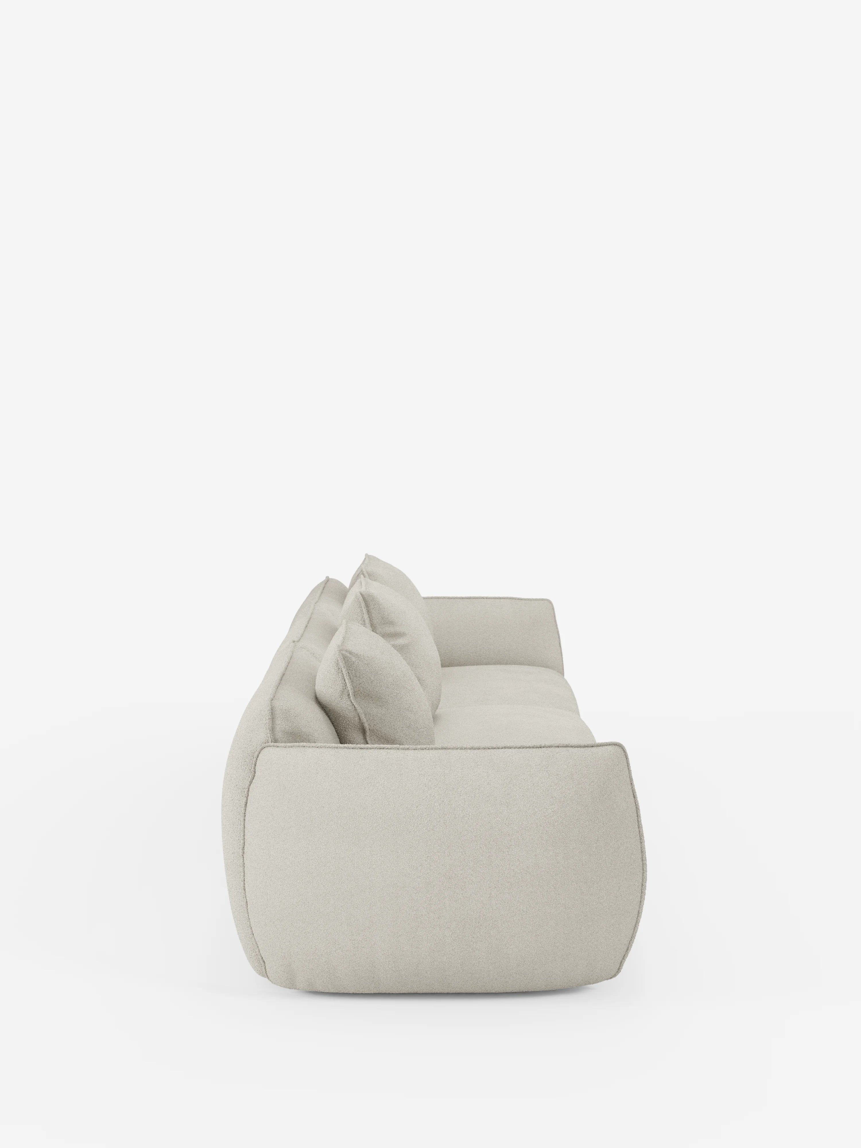 Un divano modulare Nimbus a 3 posti, in beige chiaro e dallo stile moderno, realizzato da Divani.Store, è raffigurato di profilo su uno sfondo bianco a tinta unita. Il divano presenta due grandi cuscini dello schienale, una silhouette bassa e arrotondata e un rivestimento soffice e dall’aspetto morbido in tessuto smacchiabile effetto cotone T33, caratterizzato da linee pulite e minimaliste.