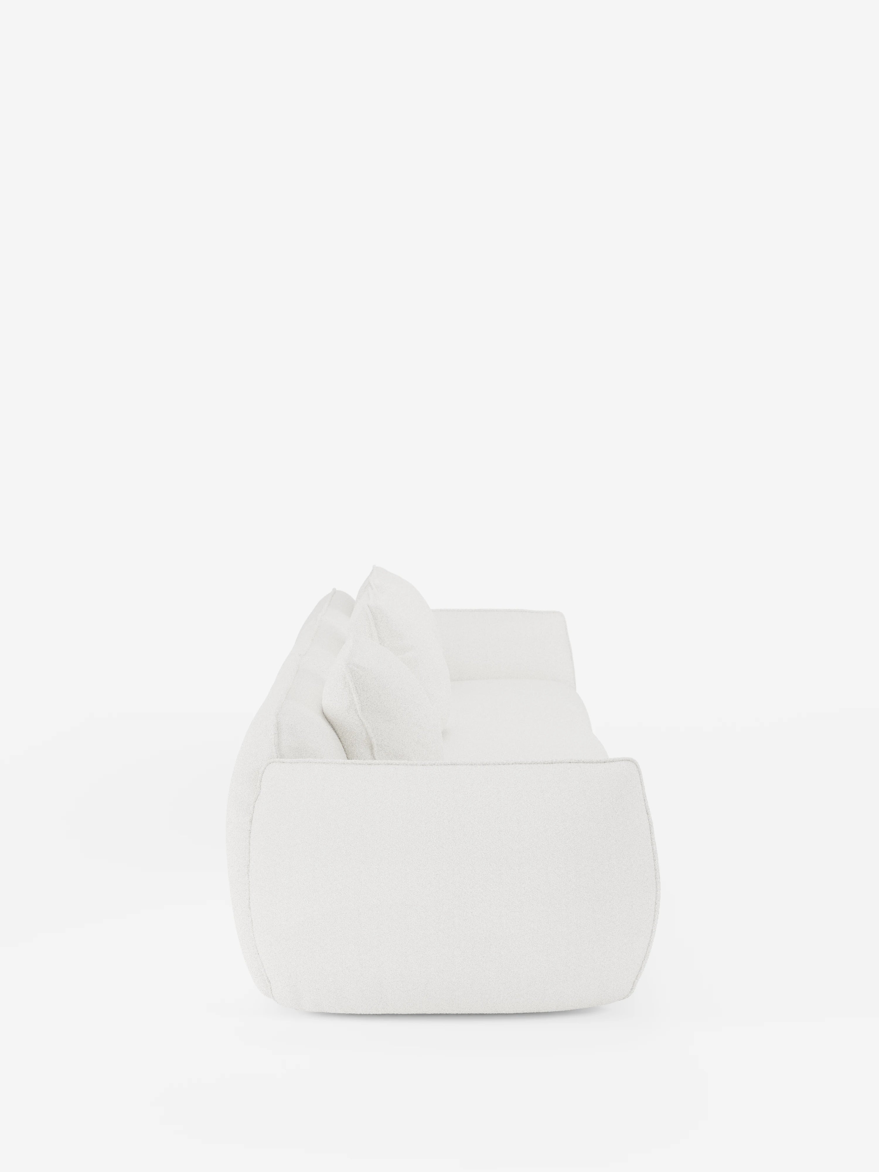 Vista laterale del divano modulare a 3 posti “Nimbus” di Divani.Store, rivestito in morbido tessuto T33 effetto cotone resistente alle macchie. Questo moderno divano bianco presenta due grandi cuscini, bordi delicatamente arrotondati e una seduta imbottita e avvolgente, per un'estetica minimalista e contemporanea. Il design sfoderabile si staglia su uno sfondo bianco a tinta unita, con un’illuminazione brillante e uniforme che ne esalta le linee eleganti.