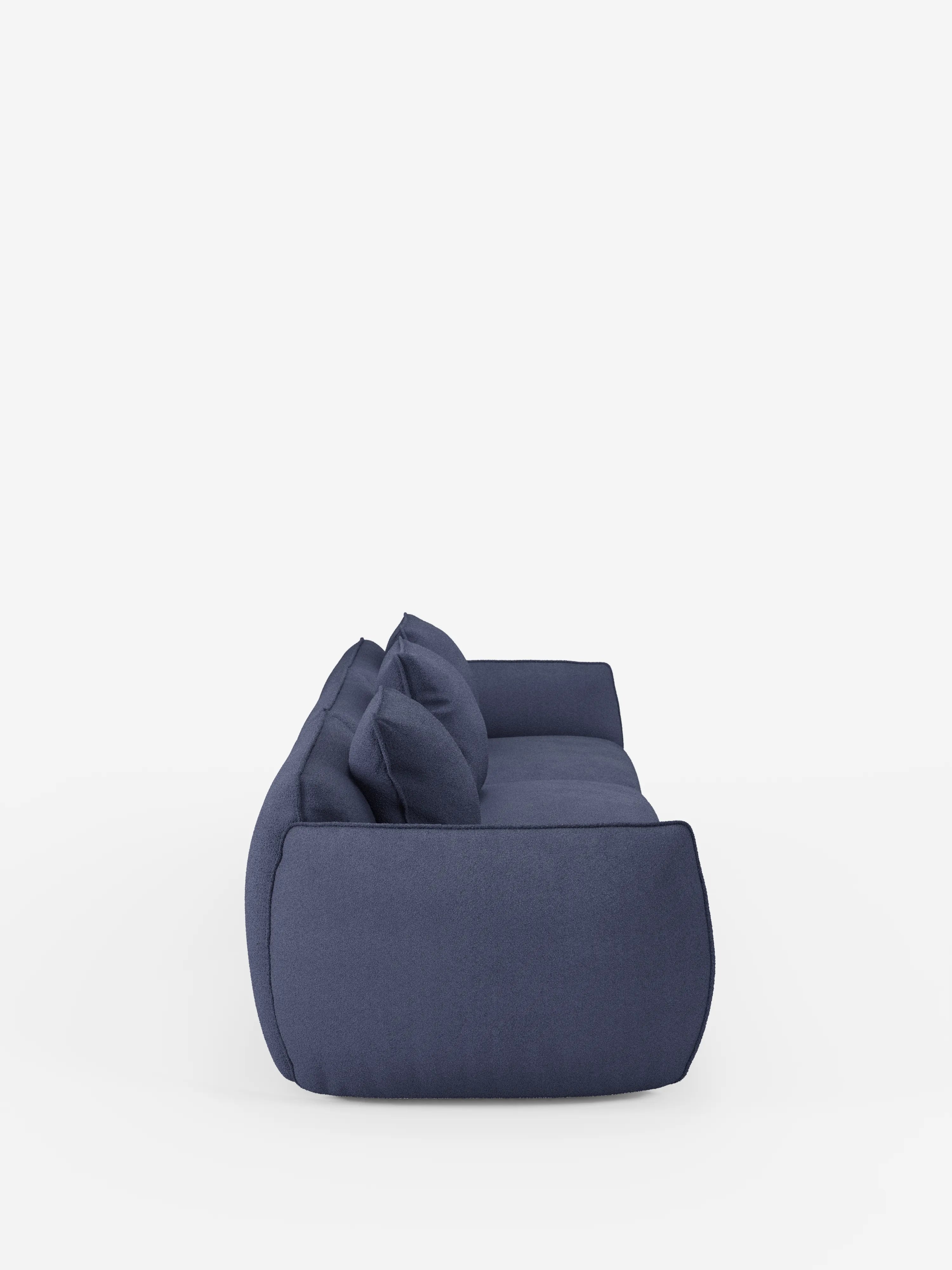 Una vista laterale del divano modulare Nimbus a 3 posti, realizzabile in morbido tessuto smacchiabile effetto cotone T33 di Divani.Store, presentato in una moderna tonalità di blu intenso con cuscini soffici e bracciolo, su uno sfondo bianco a tinta unita. Il divano appare morbido e confortevole, caratterizzato da un design semplice e dalle linee pulite e da uno stile minimalista.