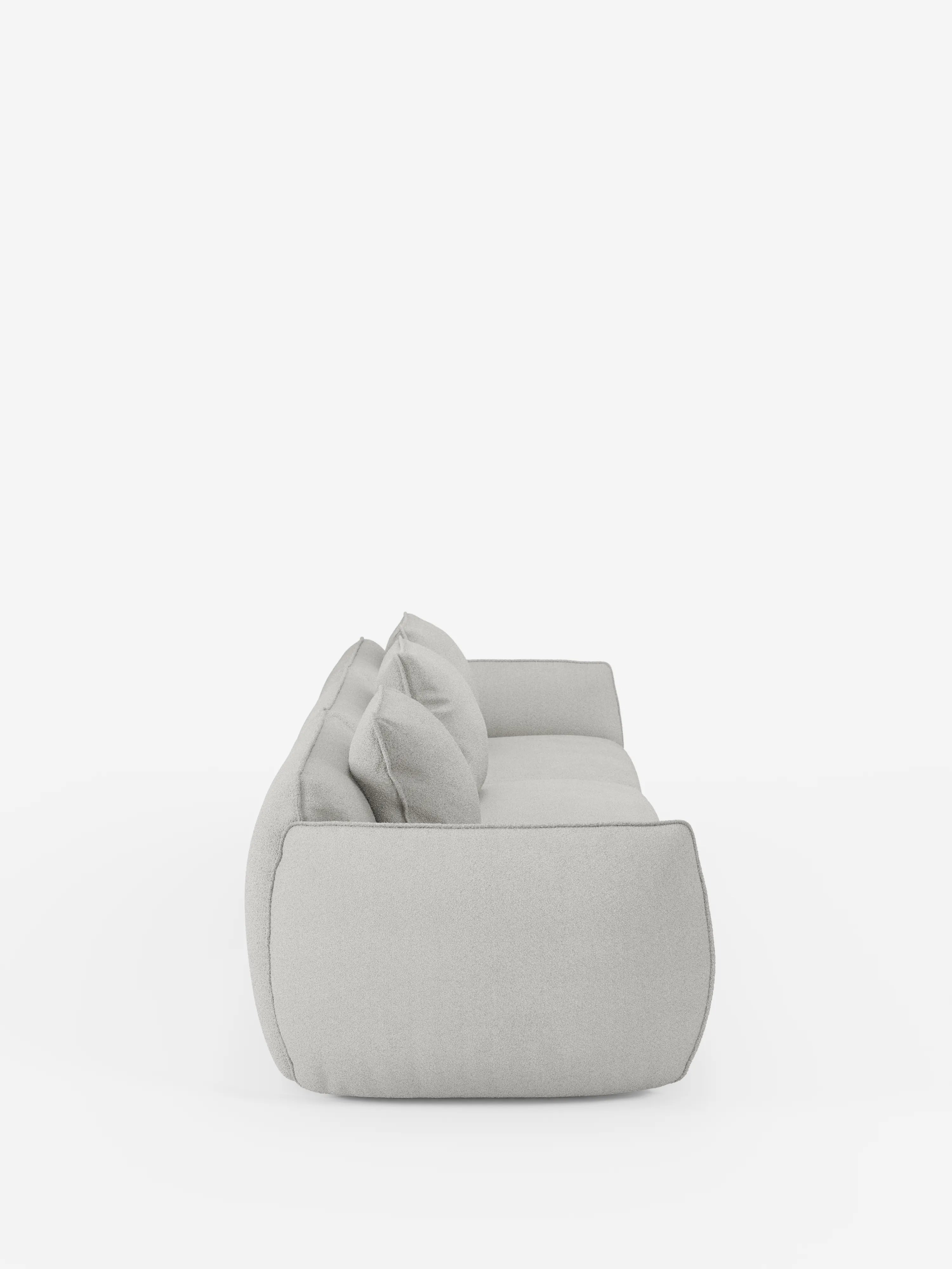 Vista laterale del divano modulare a 3 posti Nimbus di Divani.Store, qui raffigurato in grigio chiaro, con tre cuscini di seduta e tre cuscini dello schienale su uno sfondo bianco a tinta unita. Questo divano moderno presenta un design morbido e arrotondato con cuscini soffici e imbottiti in tessuto T33 effetto cotone di facile pulizia e senza gambe a vista.