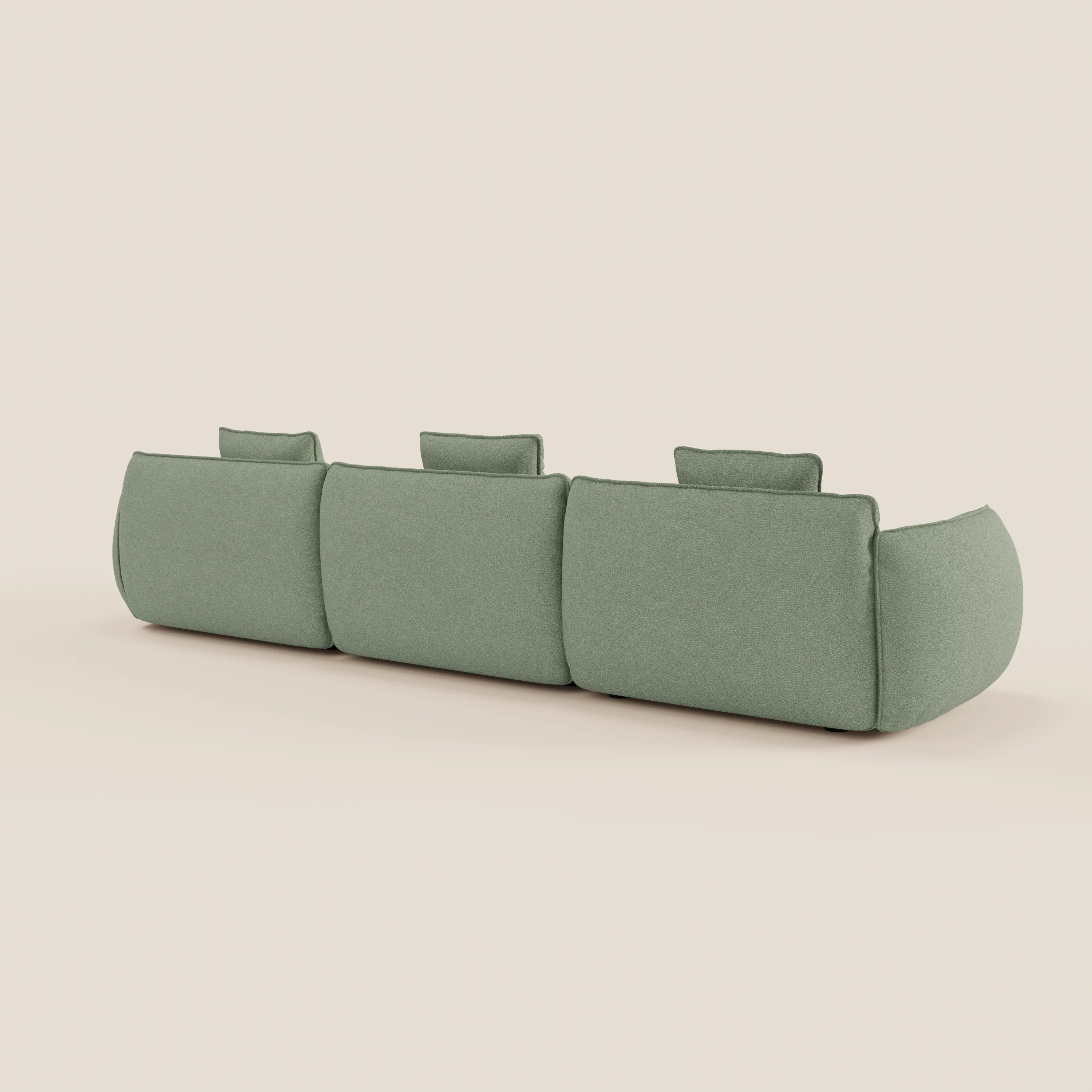 Il divano Nimbus angolare con penisola di Divani.Store è presentato dal retro in verde chiaro, con tre ampi schienali e braccioli arrotondati. Il suo design morbido e minimale è inserito in uno sfondo neutro. Rivestito in tessuto effetto cotone T33, facile da pulire.