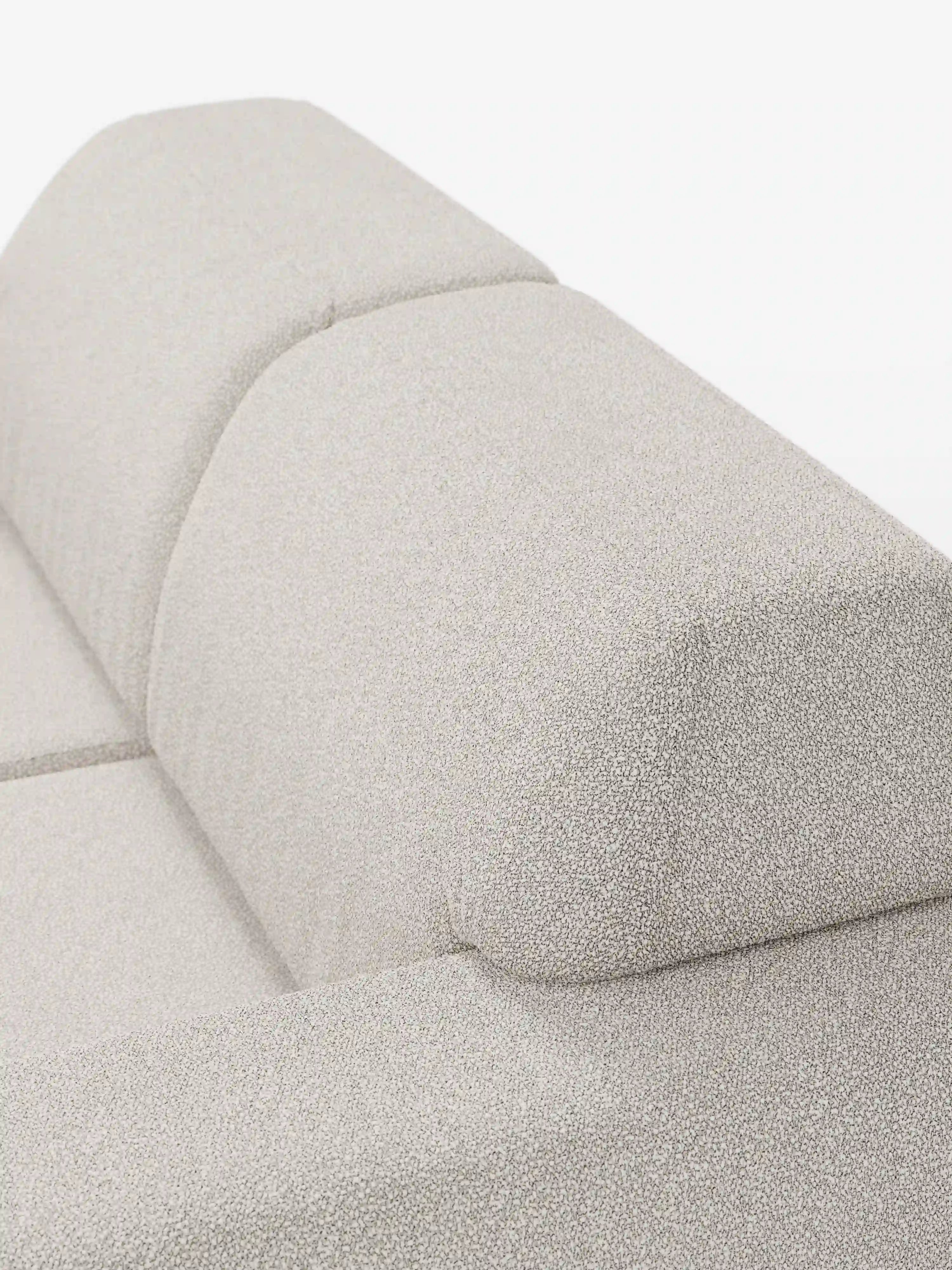 Primo piano di un divano in tessuto beige chiaro con trama a vista di Divani.Store, con particolare attenzione alla parte superiore dello schienale e dei braccioli. Il rivestimento del divano Orbit a 3 posti con sedute scorrevoli – completamente sfoderabile in tessuto smacchiabile effetto cotone T33 – appare morbido e soffice, con cuciture a vista che dividono lo schienale in sezioni, un tratto distintivo del design contemporaneo. Questo divano a 3 posti risalta su uno sfondo bianco a tinta unita.