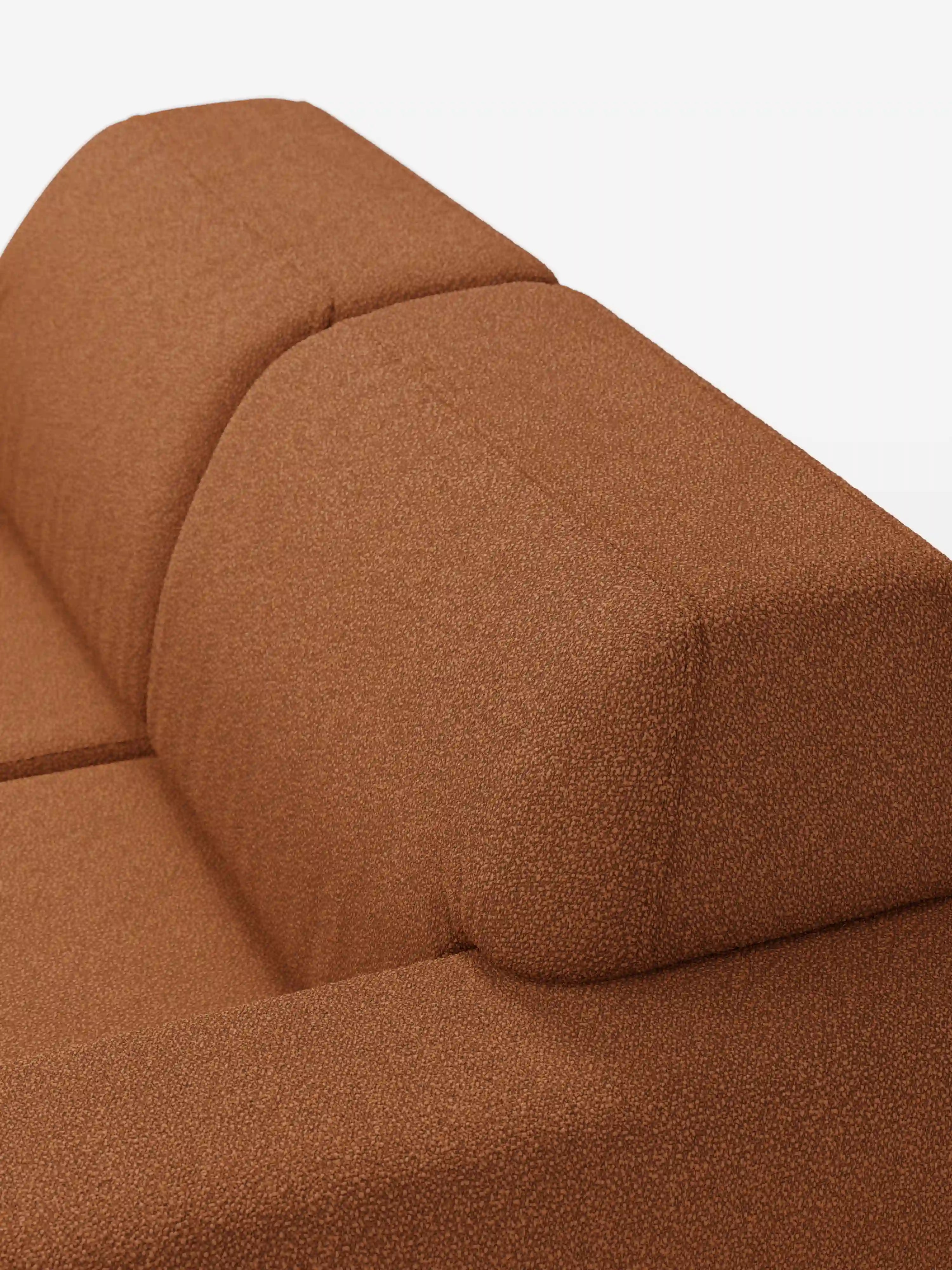 Primo piano del divano Orbit a 2 e 3 posti con sedute scorrevoli di Divani.Store, rivestito in tessuto smacchiabile T33 color ruggine con effetto cotone e trama a rilievo. Lo schienale e la seduta di questo divano moderno presentano linee pulite, una silhouette geometrica e un morbido rivestimento imbottito — interamente sfoderabile — che risalta su uno sfondo bianco a tinta unita. Un elegante divano moderno che coniuga perfettamente stile e comfort.