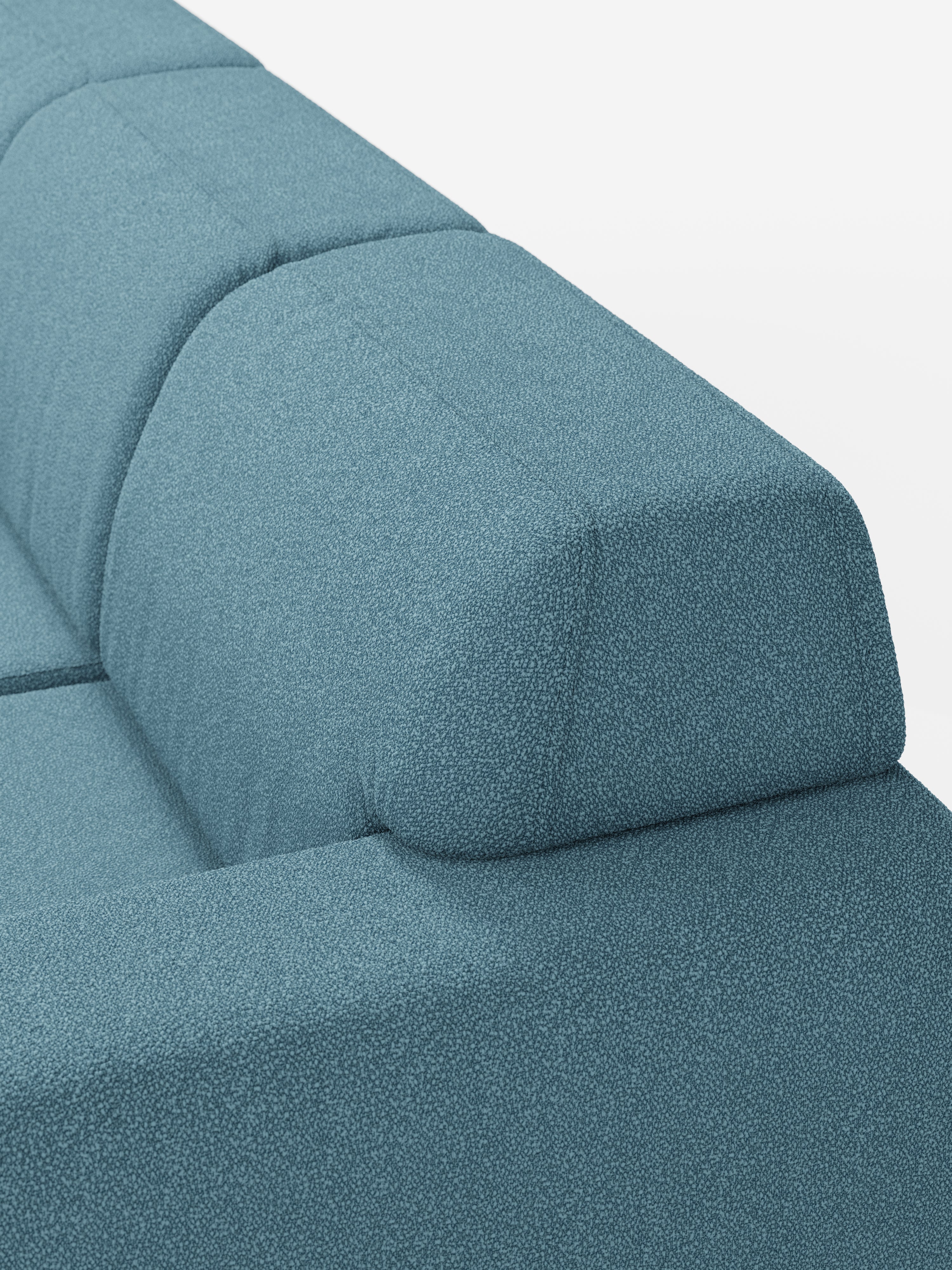 Primo piano del divano angolare Orbit con penisola reversibile e tutte le sedute allungabili di Divani.Store, rivestito in tessuto smacchiabile effetto cotone T33 in una moderna tonalità di blu. La foto mette in risalto le cuciture pulite sullo schienale e sui braccioli, nonché il design semplice e spigoloso del divano. Sullo sfondo bianco a tinta unita, l’immagine sottolinea sia la forma versatile che il colore vivace di questo elemento modulare.
