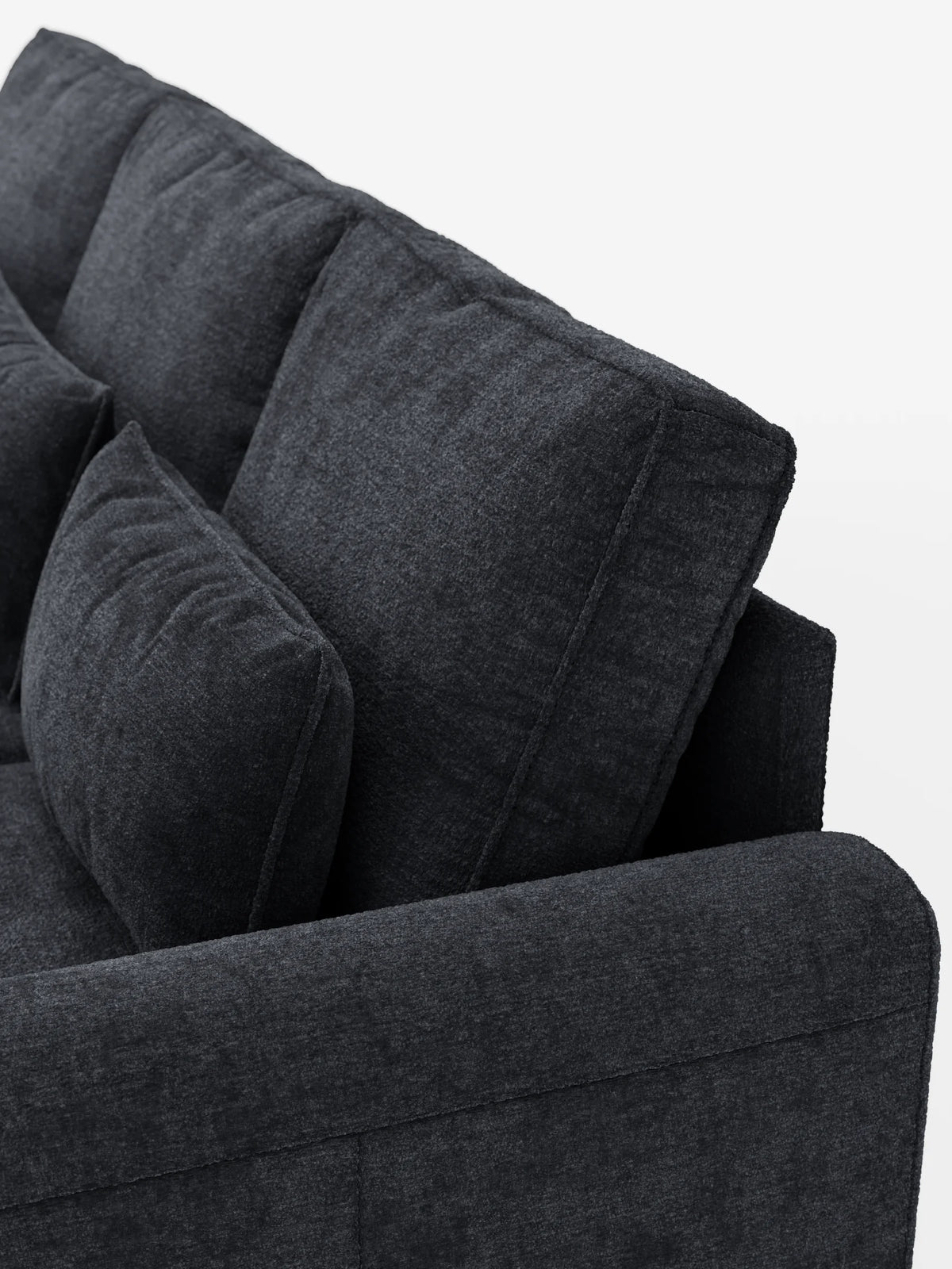 Un primo piano di un divano letto Ottaviano grigio antracite con letto estraibile – penisola reversibile e contenitore in tessuto materico smacchiabile, caratterizzato da cuscini dello schienale spessi e da un cuscino decorativo rettangolare su sfondo bianco.