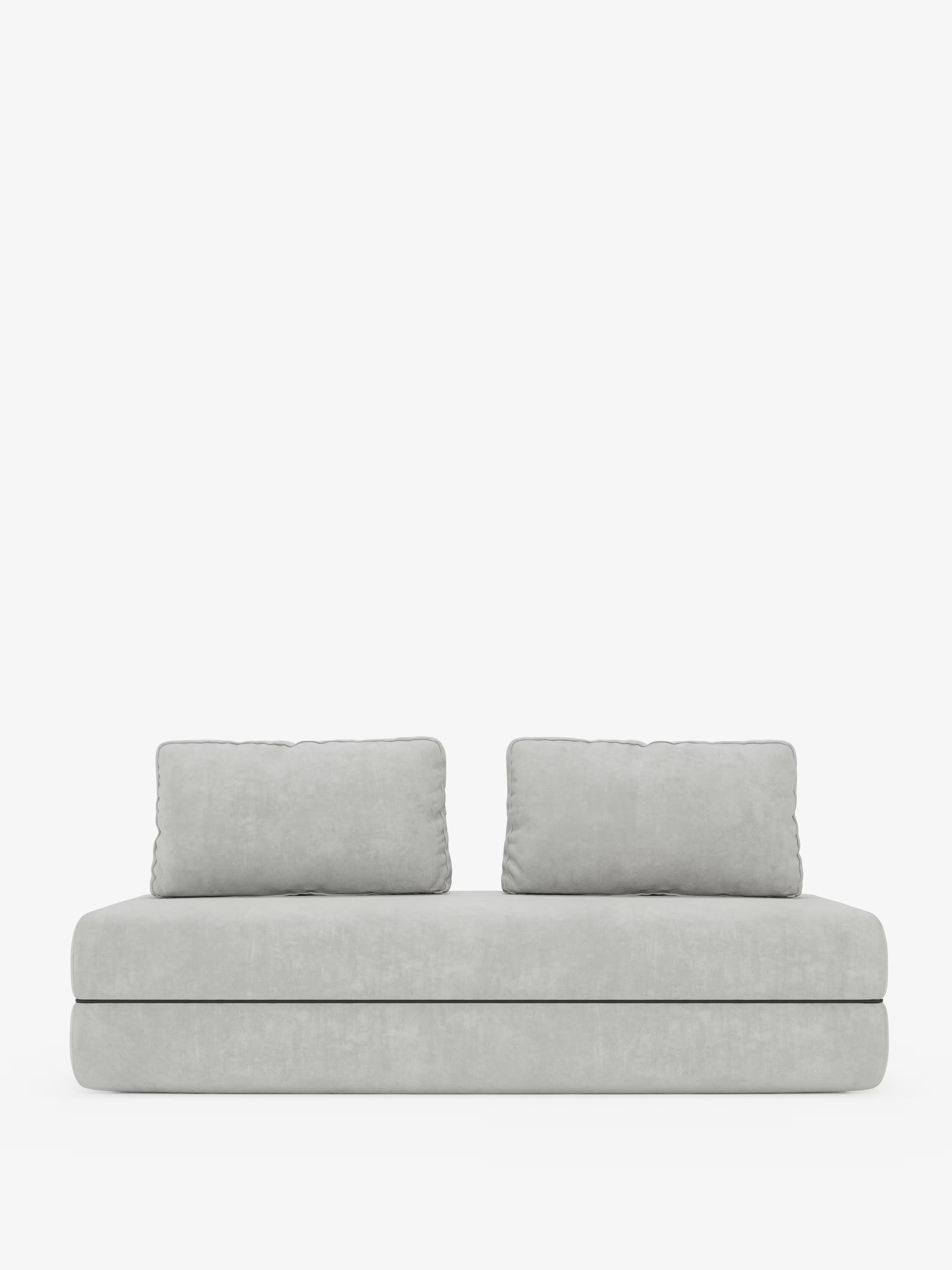 Un divano letto matrimoniale minimalista della linea Rift di Divani.Store, realizzato in tessuto T31 grigio chiaro e resistente alle macchie, è dotato di due morbidi cuscini rettangolari per lo schienale e di un cuscino di seduta spesso con un materasso in memory foam alto 24 cm. Il suo design semplice e moderno risalta sullo sfondo bianco.