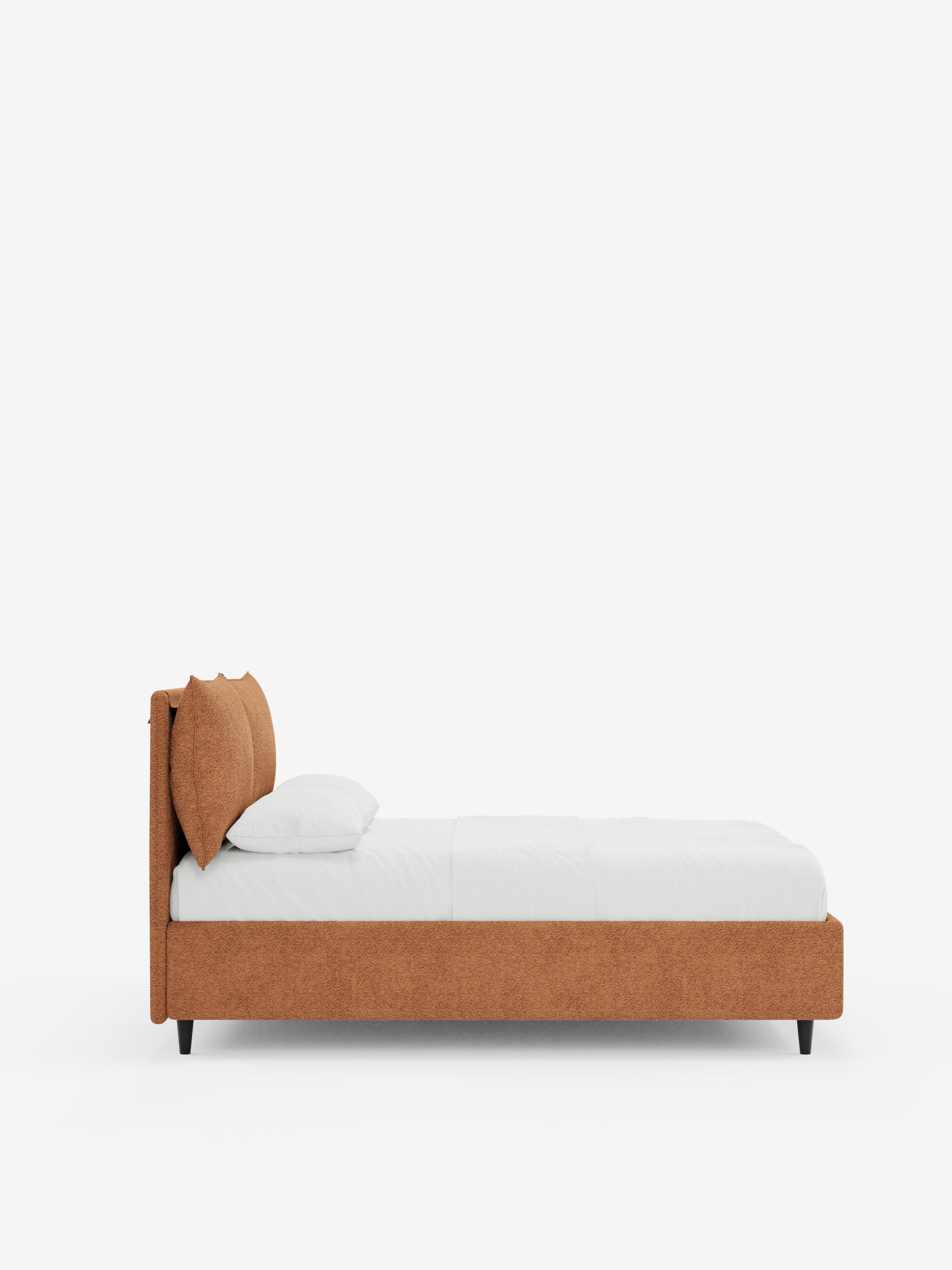 Vista laterale del letto imbottito ZAYRON con contenitore e morbidi cuscini regolabili di Letti.store, caratterizzato da un rivestimento in tessuto arancione bruciato certificato Oeko-Tex®, gambe basse nere, un materasso bianco, lenzuola bianche e due cuscini bianchi, il tutto su uno sfondo bianco a tinta unita. La testata regolabile, leggermente ricurva e imbottita, esalta sia il comfort che lo stile di questo design moderno.