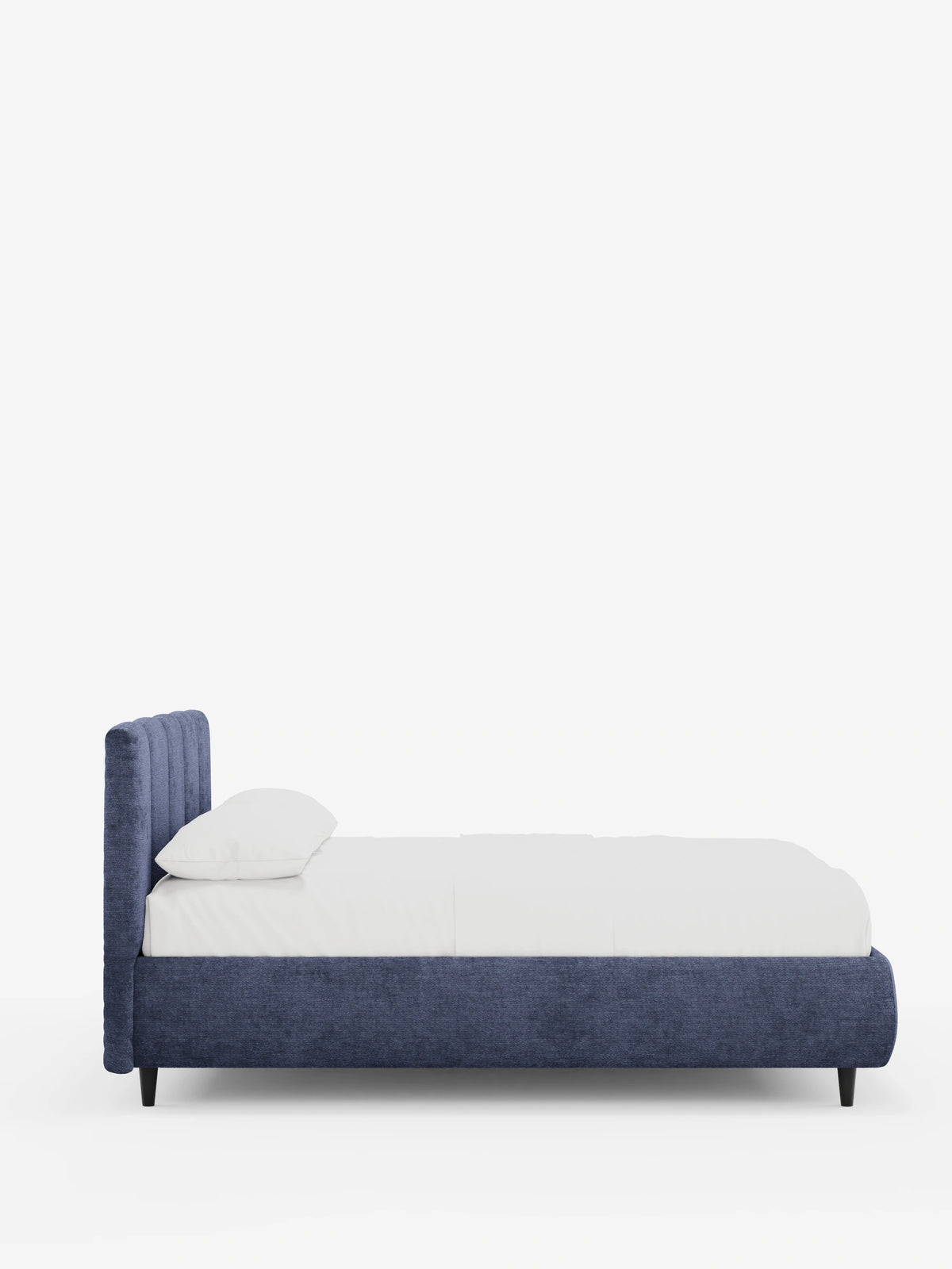Vista laterale di un letto imbottito ARKAM blu scuro con contenitore e testiera a lavorazione verticale, caratterizzato da cuciture verticali, biancheria da letto candida, un unico cuscino e sottili gambe nere su uno sfondo bianco a tinta unita.