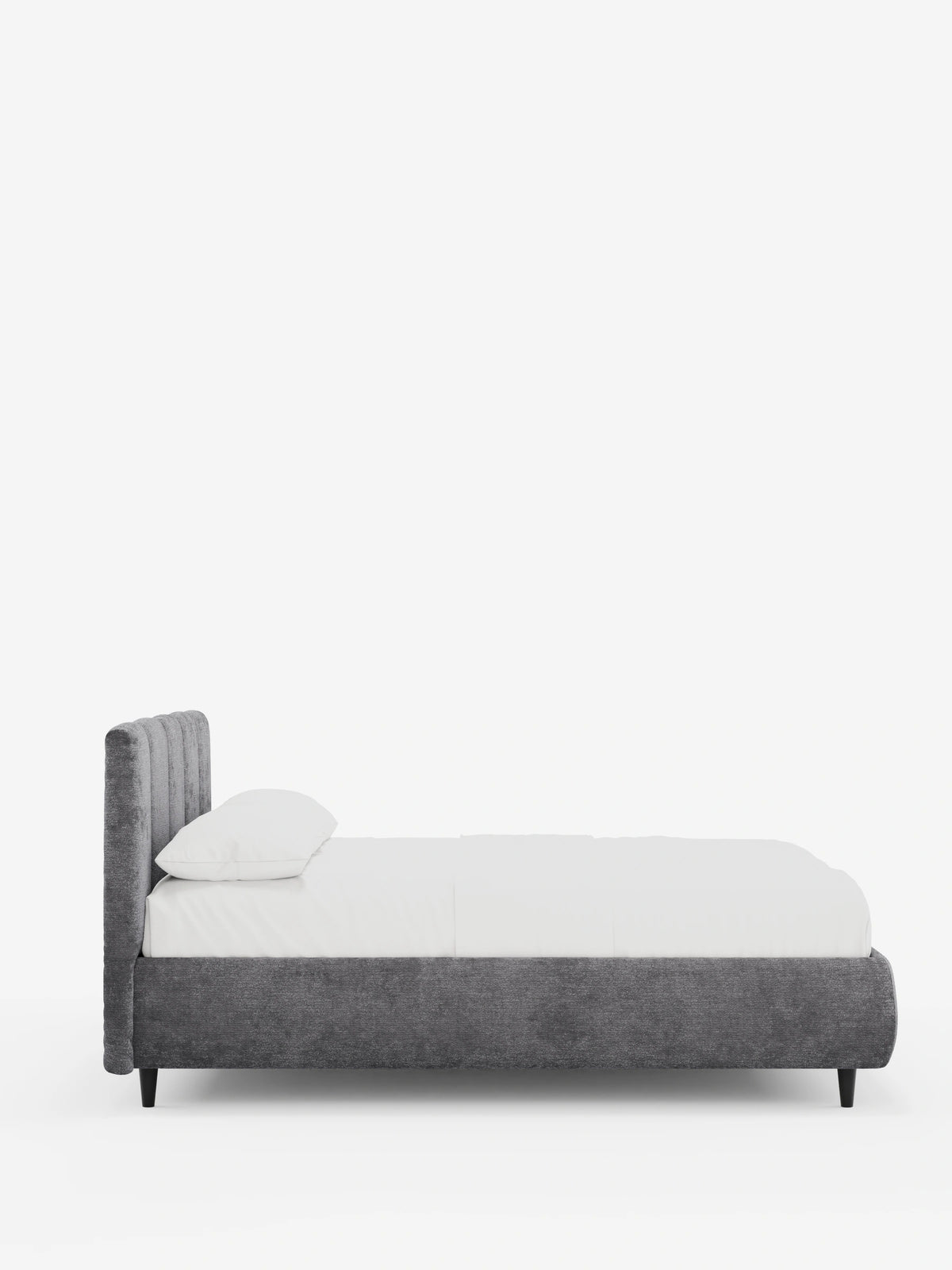 Il letto imbottito ARKAM con contenitore e testiera con cuciture verticali è un letto imbottito grigio con cuciture verticali, biancheria da letto bianca e un cuscino singolo, appoggiato su gambe corte nere affusolate su uno sfondo bianco.