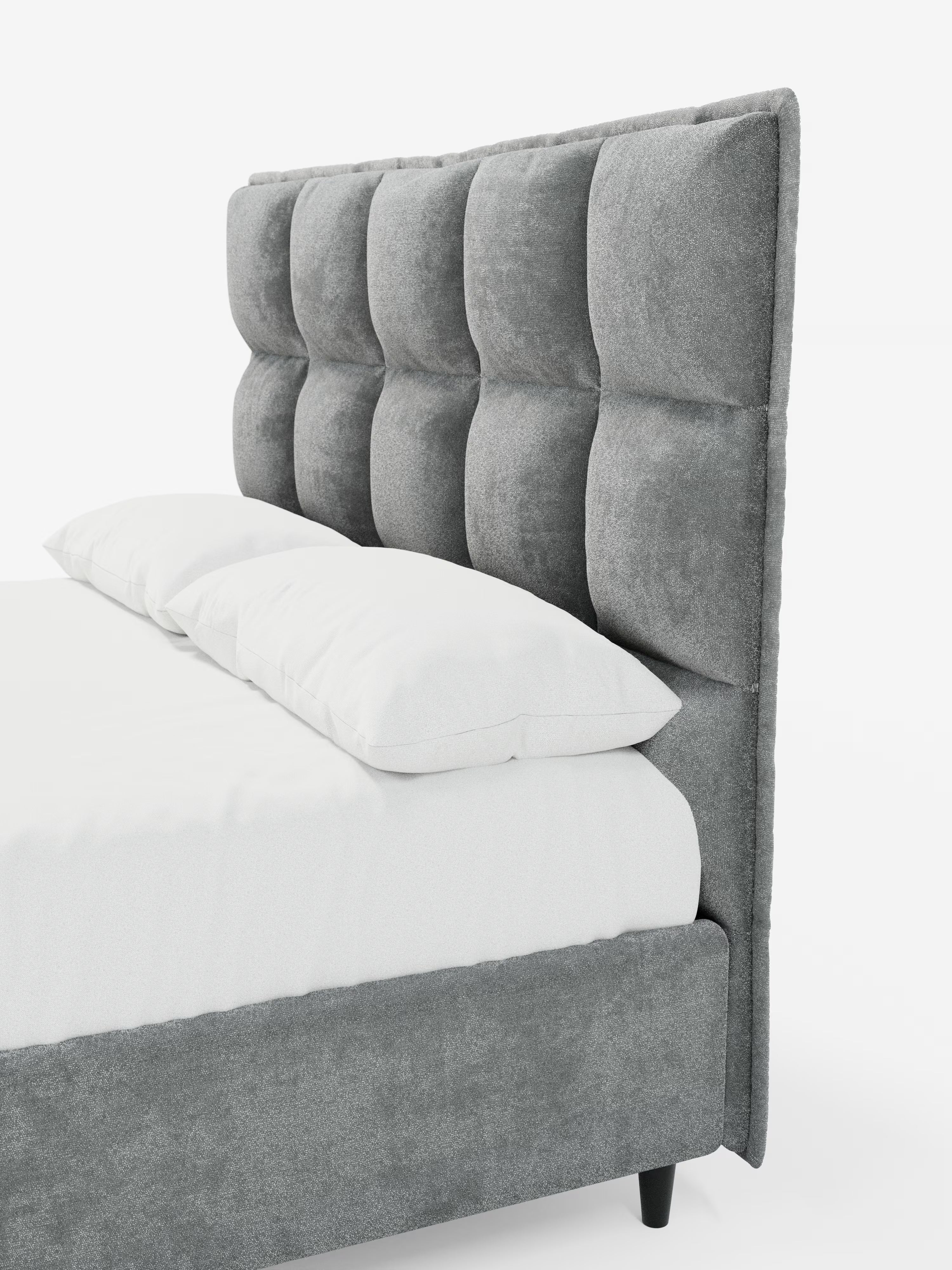Il letto imbottito AURO con contenitore e testiera capitonné alta in ciniglia Oeko-Tex® di Letti.store presenta una struttura imbottita grigia con una testiera alta a sezione quadrata, rifinita con un elegante motivo capitonné. Questo letto di Letti.store include un materasso bianco e due cuscini bianchi, poggia su gambe corte nere e si presenta su uno sfondo bianco a tinta unita.