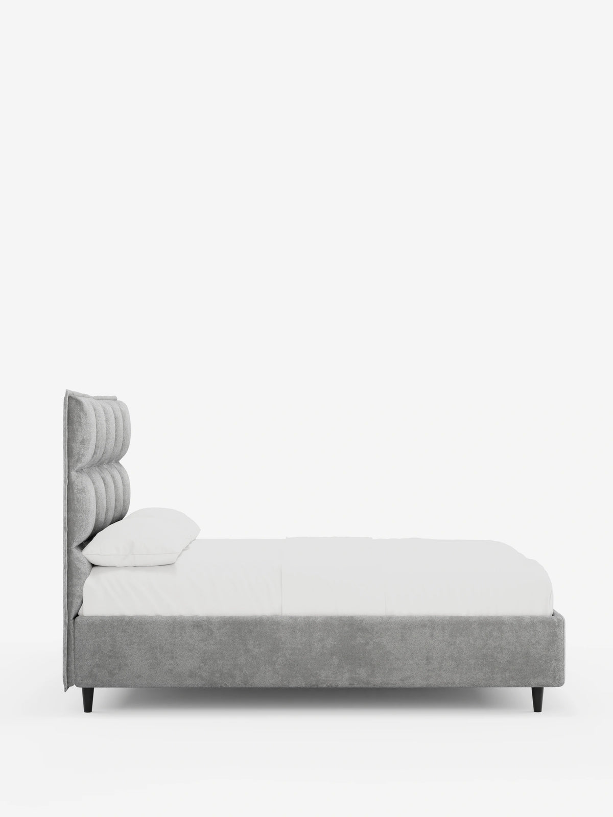 Vista di profilo di un letto imbottito AURO grigio con contenitore e testiera capitonné alta in ciniglia Oeko-Tex®, con piedini scuri, rivestito con lenzuola bianche su uno sfondo grigio chiaro.