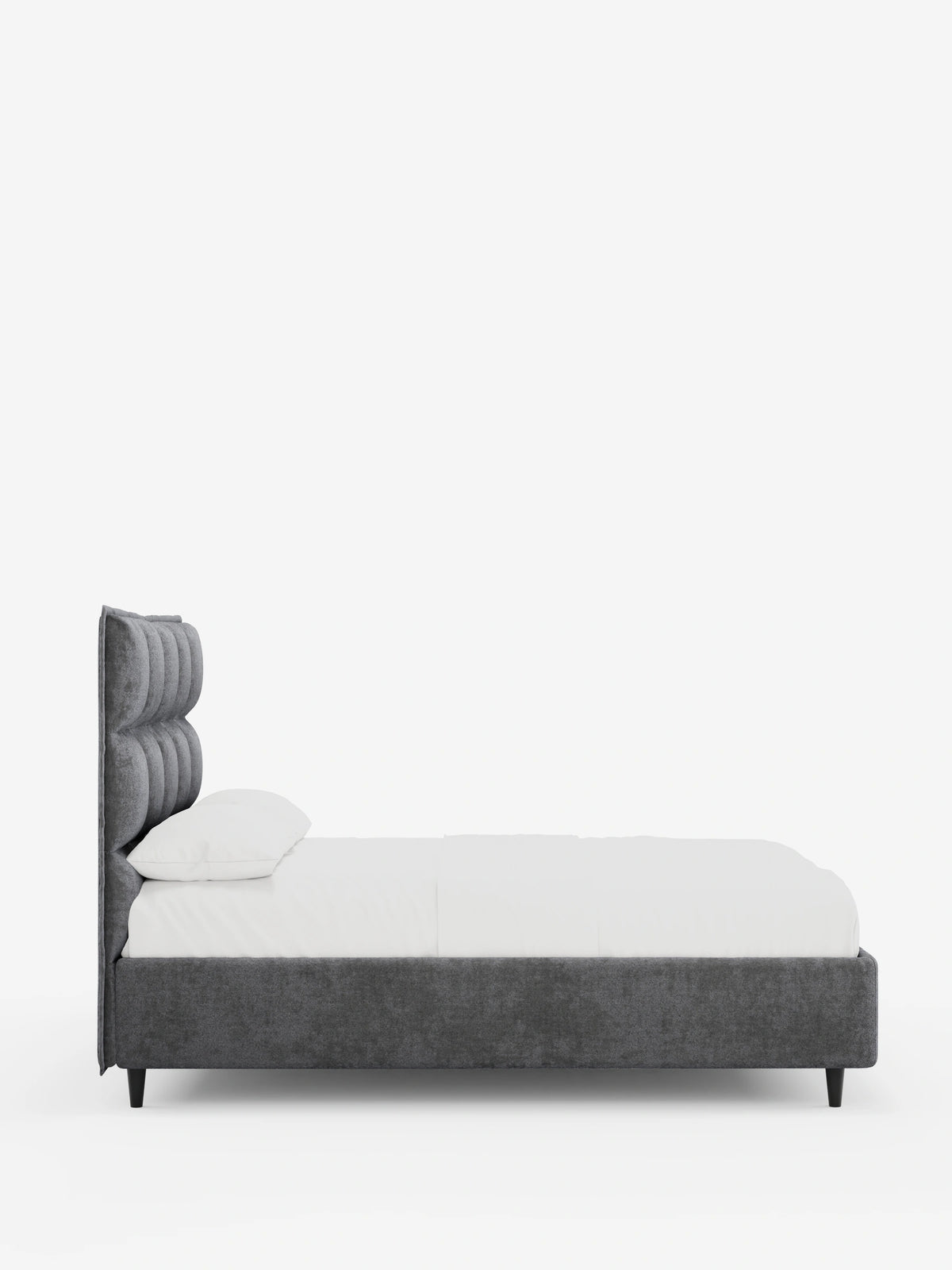 Un letto imbottito AURO color grigio antracite, dotato di vano contenitore e testiera alta capitonné in ciniglia Oeko-Tex®, spicca su uno sfondo bianco a tinta unita, con un materasso bianco e un cuscino abbinato, il tutto sostenuto da piccole gambe affusolate di colore scuro.