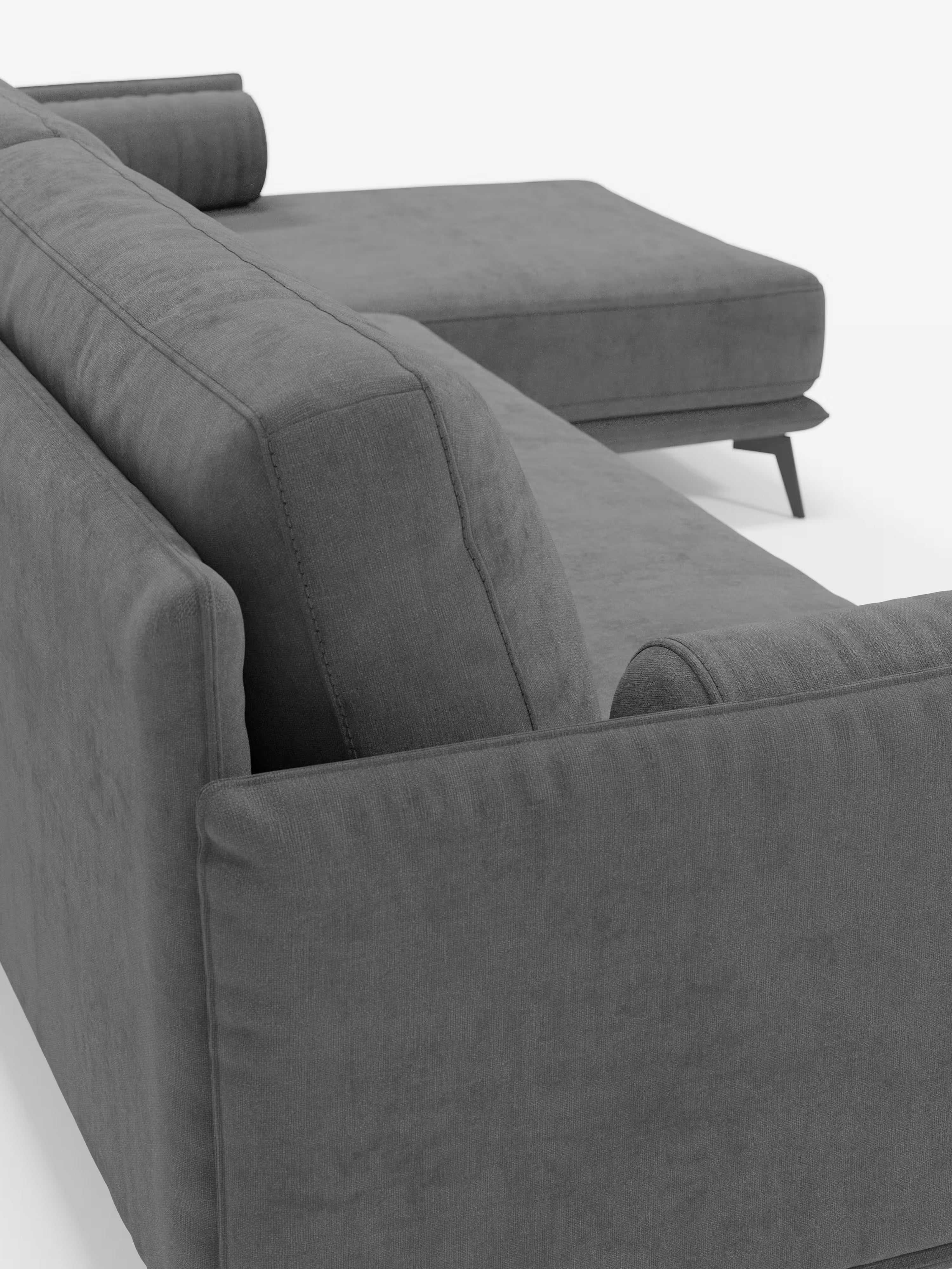 Un primo piano del “Basalto Divano moderno angolare con penisola” di Divani.Store: un moderno divano componibile italiano in grigio scuro, caratterizzato da ampi braccioli, gambe angolari in metallo e cuscini cilindrici imbottiti in piuma. Rivestito in morbido tessuto T31 resistente alle macchie, dalle linee pulite e dal design minimalista, su uno sfondo bianco a tinta unita.