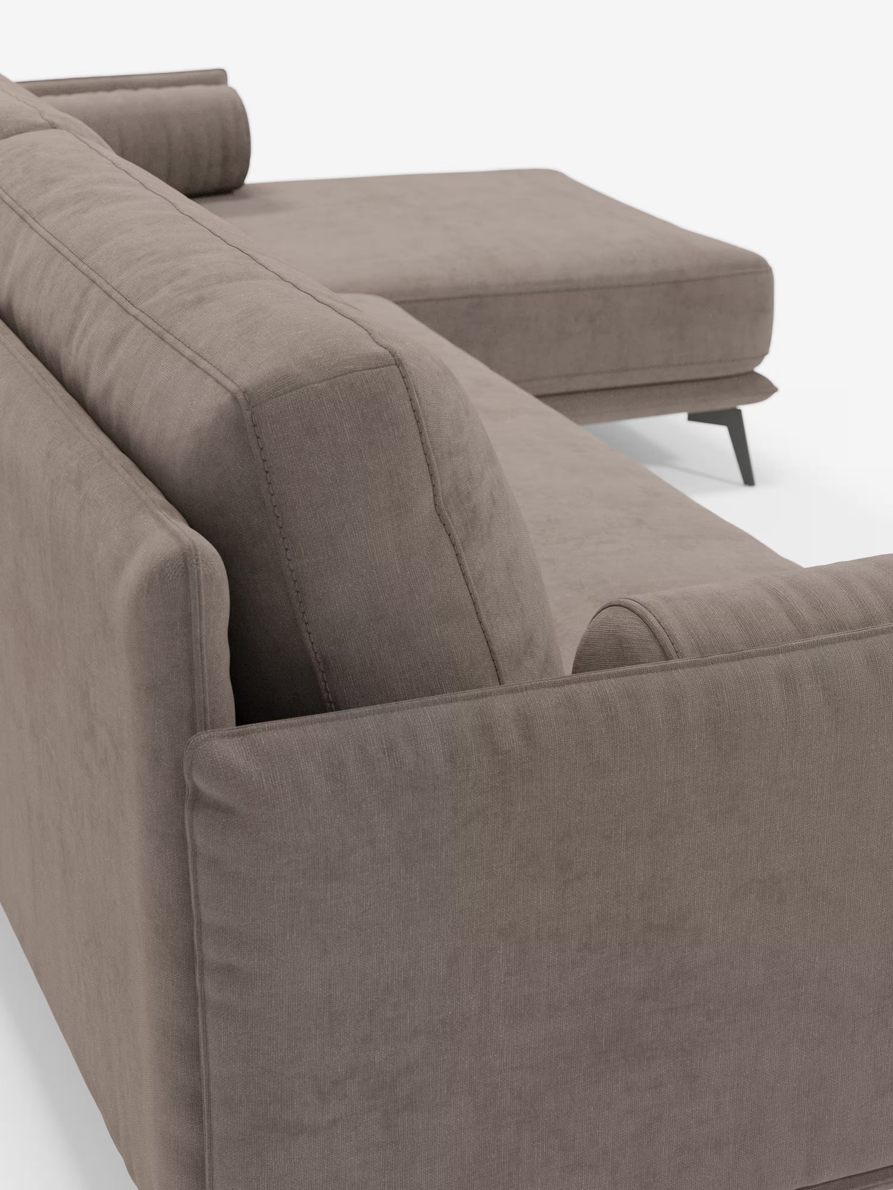 Primo piano del divano moderno angolare con penisola “Basalto” di Divani.Store, rivestito in tessuto T31 antimacchia con un rivestimento elegante e sfoderabile. Il divano componibile presenta linee pulite, cuscini dello schienale leggermente inclinati con imbottitura in piuma, due cuscini cilindrici e gambe affusolate di colore scuro su una base in metallo. La sua elegante sezione chaise longue si estende verso destra, il tutto su uno sfondo bianco a tinta unita.