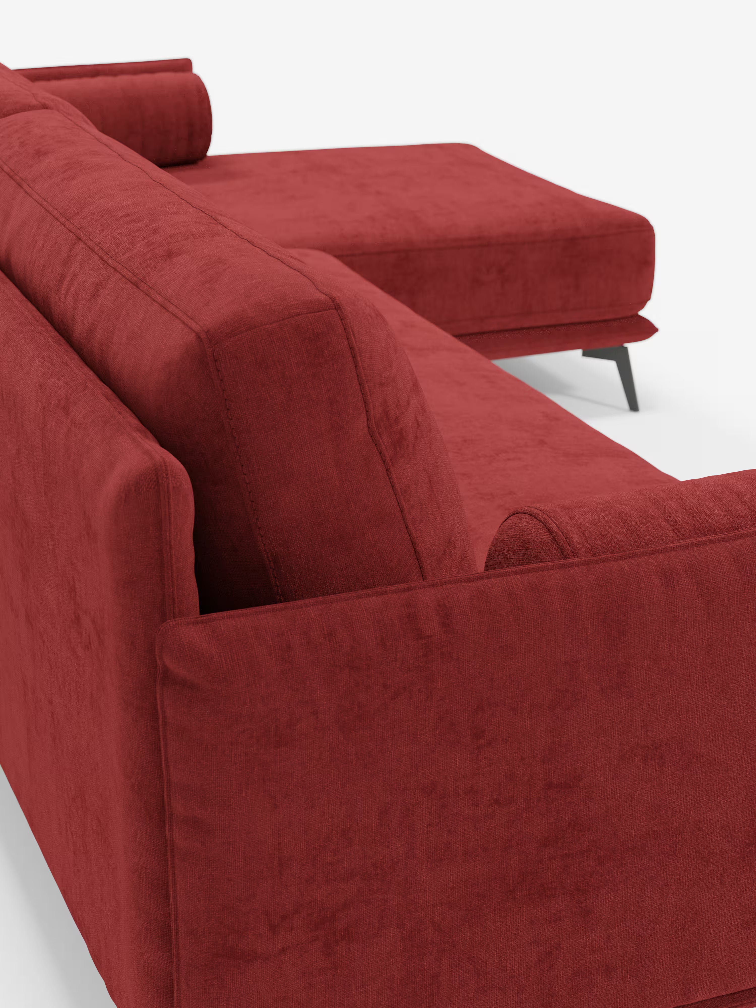 Un primo piano del “Basalto Divano moderno angolare con penisola” di Divani.Store mette in risalto questo divano componibile contemporaneo di colore rosso, caratterizzato da un rivestimento in morbido tessuto T31 resistente alle macchie, uno schienale angolare e un cuscino cilindrico abbinato. La sezione chaise longue si estende verso destra ed è sostenuta da eleganti gambe in metallo nero, il tutto su uno sfondo bianco a tinta unita: un vero esempio di eleganza moderna con cuscini imbottiti in piuma.