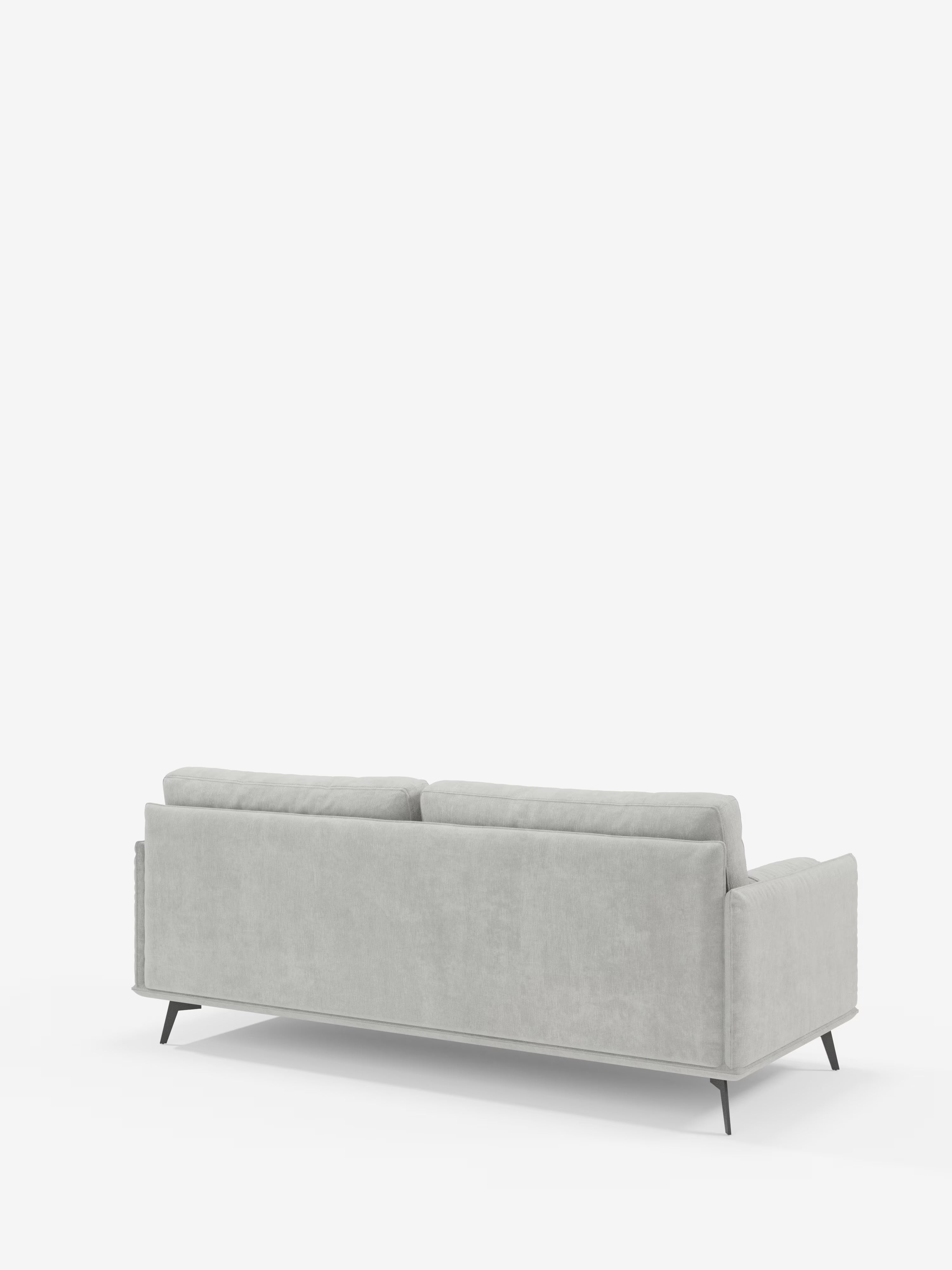 Il divano Basalto, un modello lineare moderno a 2 o 3 posti con seduta unica e base in metallo, di colore grigio chiaro, realizzato da Divani.Store, è raffigurato di retro, con le sue linee pulite, i morbidi cuscini e le sottili gambe angolate di colore nero. Questo elegante divano è rivestito in tessuto smacchiabile T31 e poggia su uno sfondo bianco con ampio spazio libero sopra di esso.