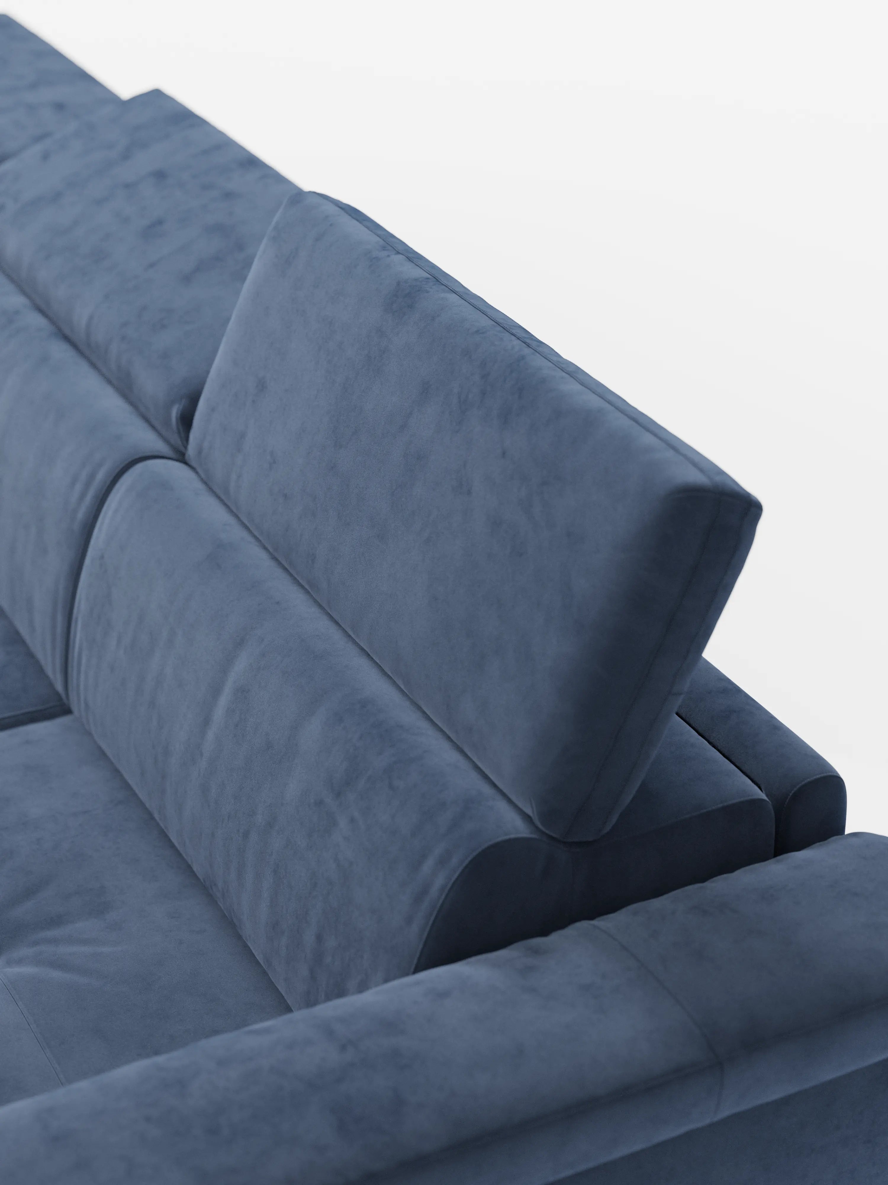 Un primo piano del divano letto angolare Capri di Divani.Store ne mette in risalto il design moderno, caratterizzato dal rivestimento in morbido e lussuoso vellutino blu smacchiabile. I poggiatesta regolabili sono inclinati verso l’alto per garantire il massimo comfort, mentre lo sfondo bianco a tinta unita mette in risalto le linee slanciate e le caratteristiche di alta prestazione di questo divano letto angolare con materasso T30.