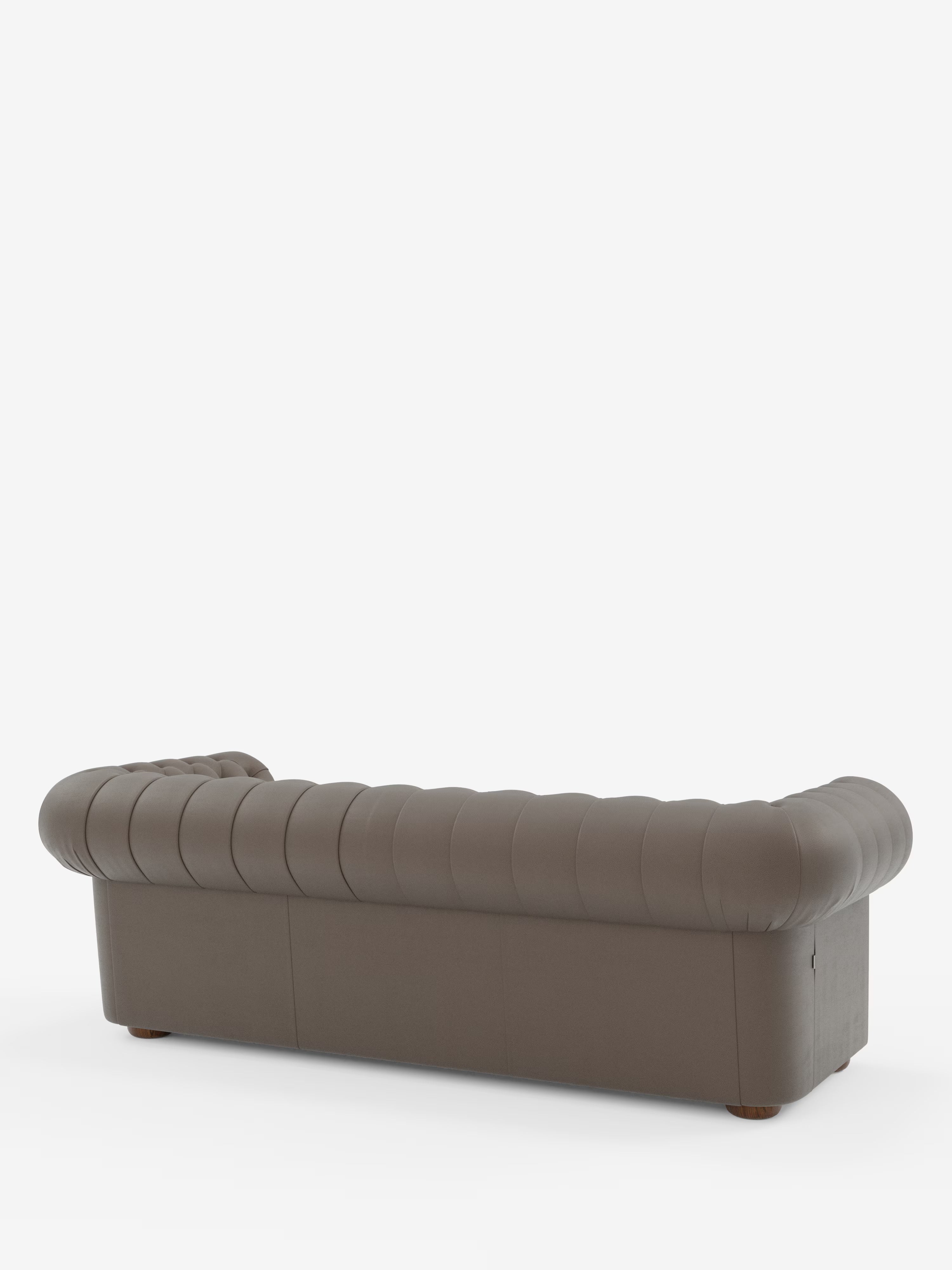 Un divano Chester 4 Posti 3 sedute in vera pelle marrone capitonné – Chesterfield Capitonné Artigianale di Divani.Store è ripreso di retro su uno sfondo bianco a tinta unita. Realizzato in vera pelle italiana, questo divano presenta braccioli arrotondati e uno schienale basso con delicati dettagli a bottoni e gambe in legno scuro appena visibili sotto.