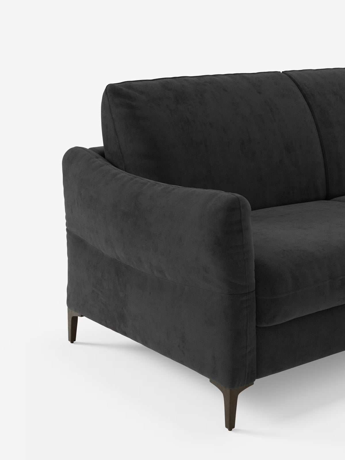 Un divano letto Dalia contemporaneo di colore grigio scuro di Divani.Store, rivestito in moderno tessuto di velluto T30 antimacchia, caratterizzato da un'imbottitura morbida, braccioli ricurvi e gambe angolate in legno scuro. Su uno sfondo bianco a tinta unita sono visibili solo il lato sinistro e una parte della seduta.