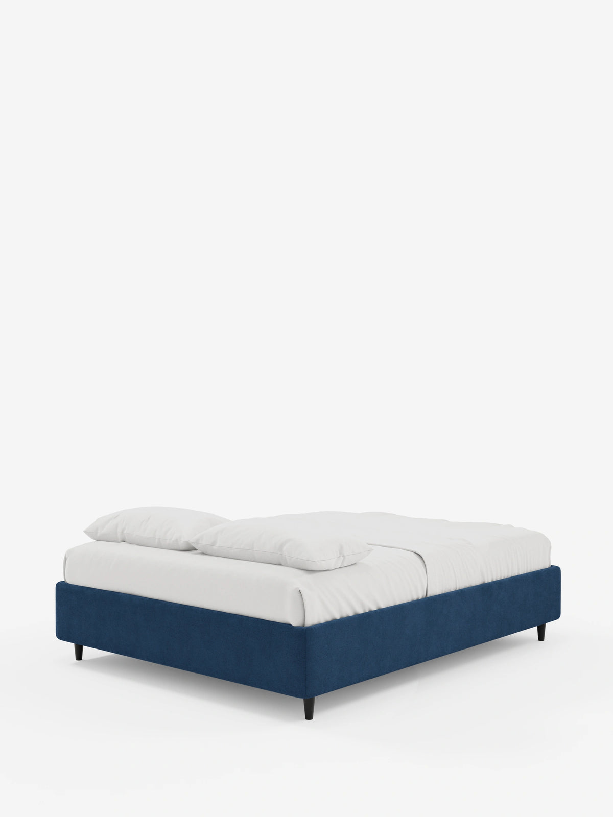 Un letto sommier ERON di colore blu intenso, imbottito e dotato di vano contenitore in tessuto impermeabile certificato Oeko-Tex, poggia su piccole gambe nere; sulla sua superficie piana, su uno sfondo bianco a tinta unita, sono disposti due cuscini bianchi e un lenzuolo bianco.