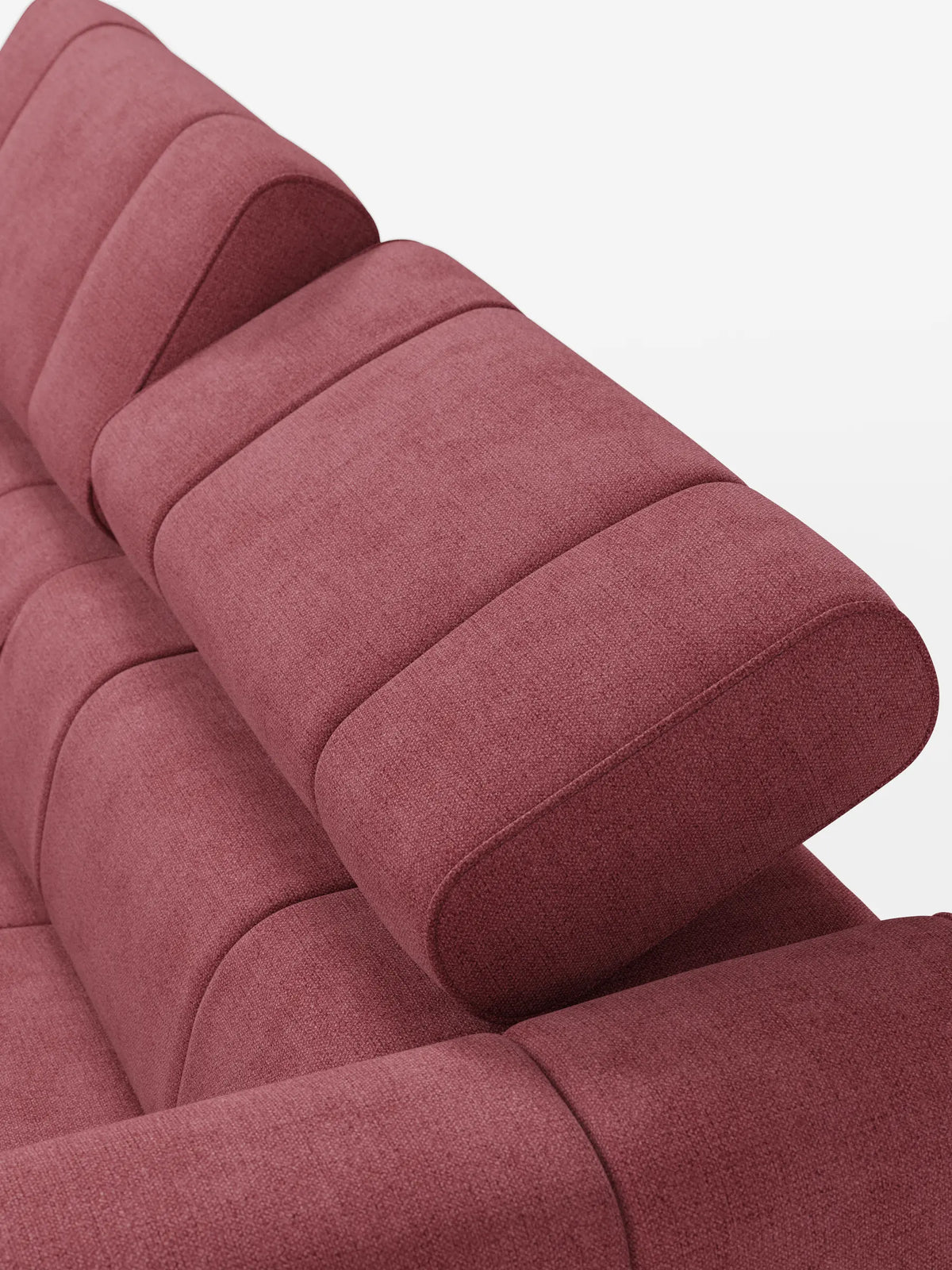 Un primo piano di un divano modulare Giotto a 3 posti color rosa polveroso, dotato di tre poggiatesta imbottiti e reclinabili e di un rivestimento in tessuto testurizzato impreziosito da sottili cuciture orizzontali.