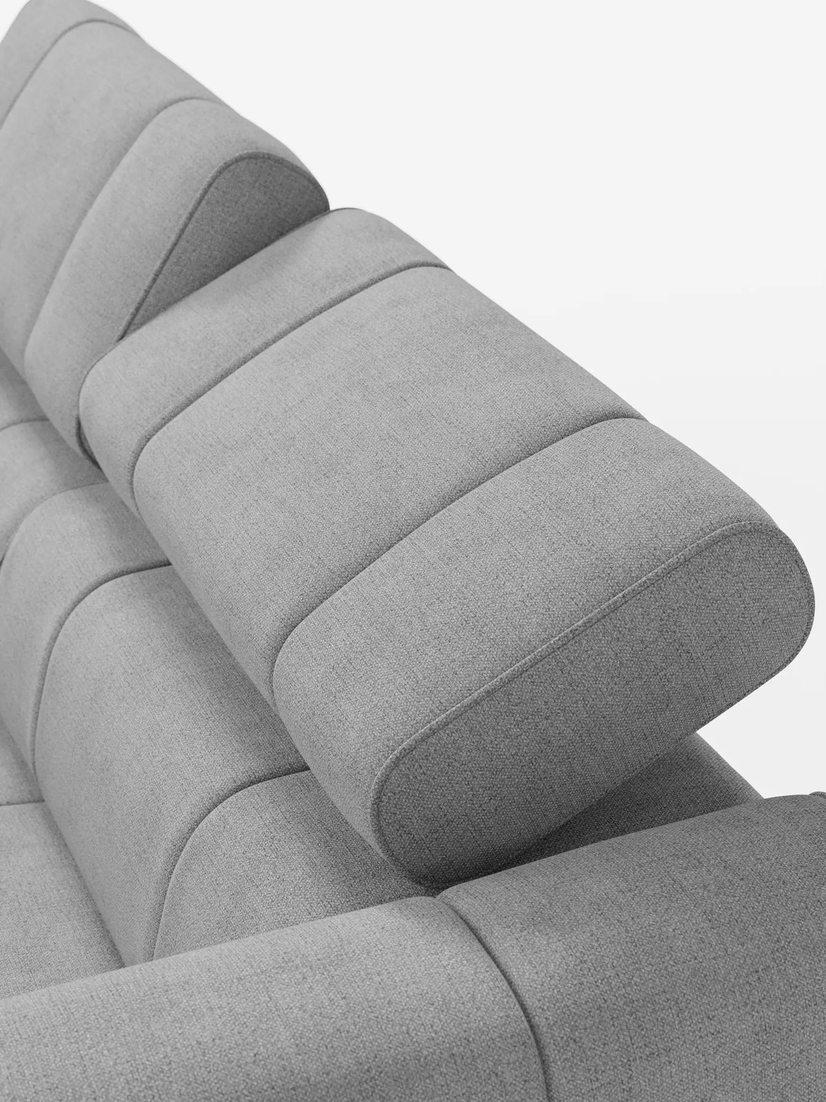Un primo piano di un divano modulare Giotto a 3 posti di colore grigio chiaro, con rivestimento in tessuto testurizzato, dotato di poggiatesta imbottiti regolabili dai bordi arrotondati, dal design contemporaneo, su uno sfondo bianco a tinta unita.
