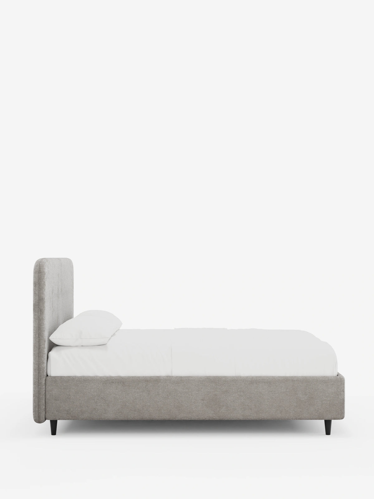 Vista laterale di un letto KAELOS minimal imbottito con testiera arrotondata rivestita in tessuto grigio, caratterizzato da biancheria da letto bianca, una struttura sottile e gambe corte, scure e affusolate, su uno sfondo bianco a tinta unita.