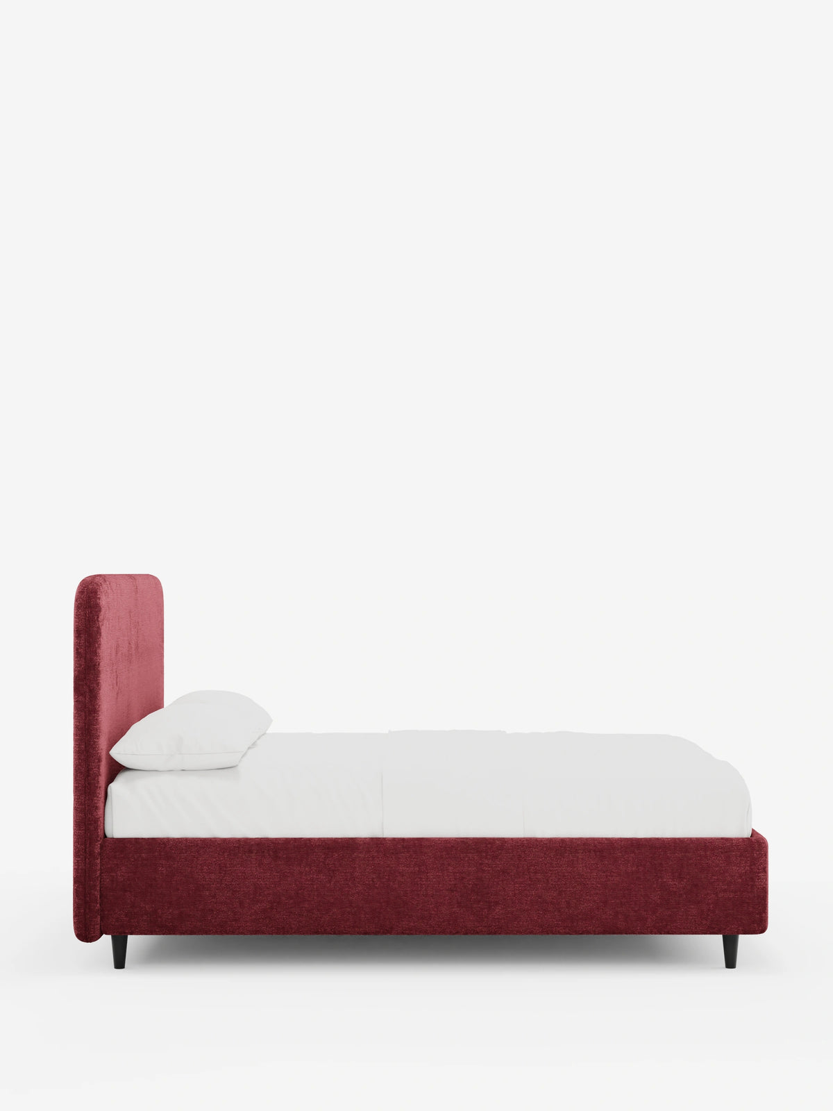 Una vista laterale di un letto KAELOS minimal imbottito con rivestimento in tessuto rosso scuro, caratterizzato da una testiera arrotondata, biancheria da letto bianca con un unico cuscino e sottili gambe nere su uno sfondo bianco a tinta unita.