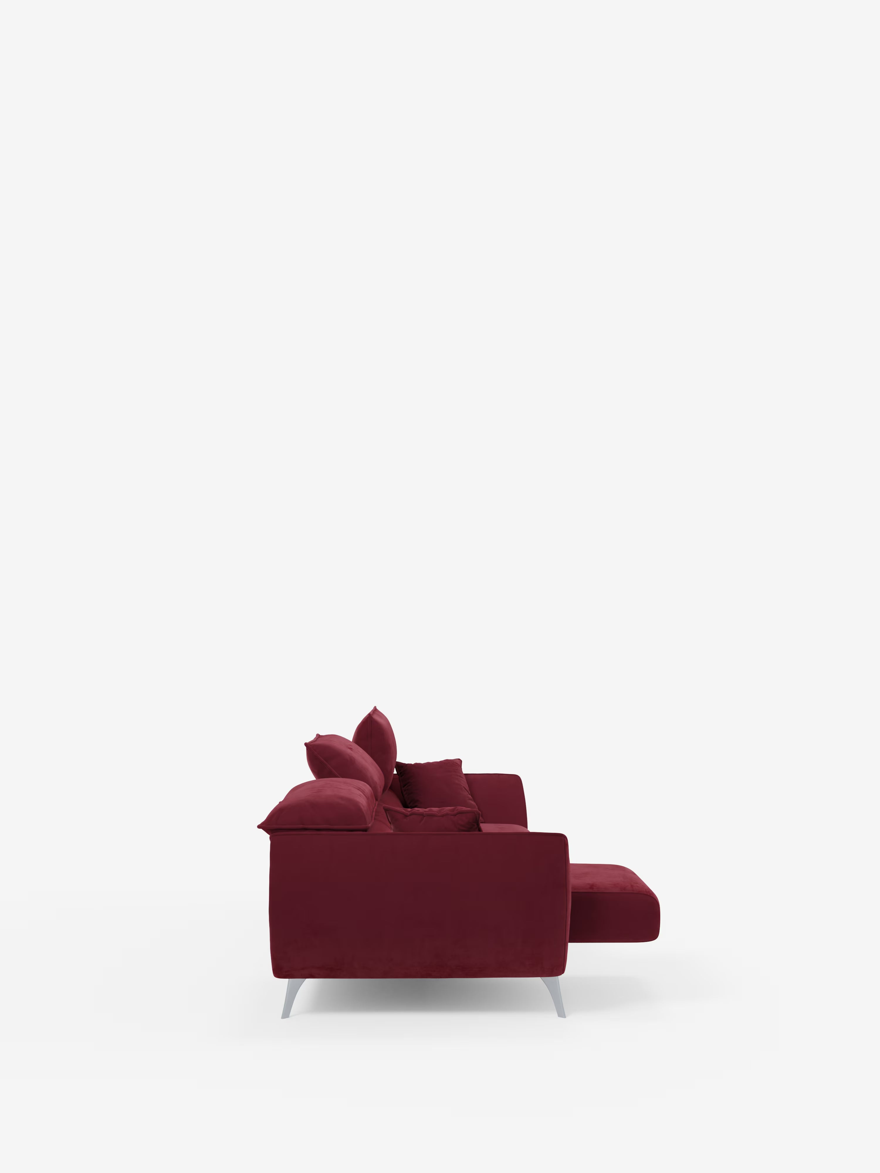 Vista laterale del divano Michelangelo 4 Posti di Divani.Store, un moderno divano rosso intenso realizzato in elegante velluto T30 antimacchia, con cuscini spessi e una chaise longue a destra. Tra le caratteristiche figurano tre sedute estensibili e poggiatesta reclinabili, messi in risalto da uno sfondo bianco a tinta unita con ampio spazio libero che circonda il divano.