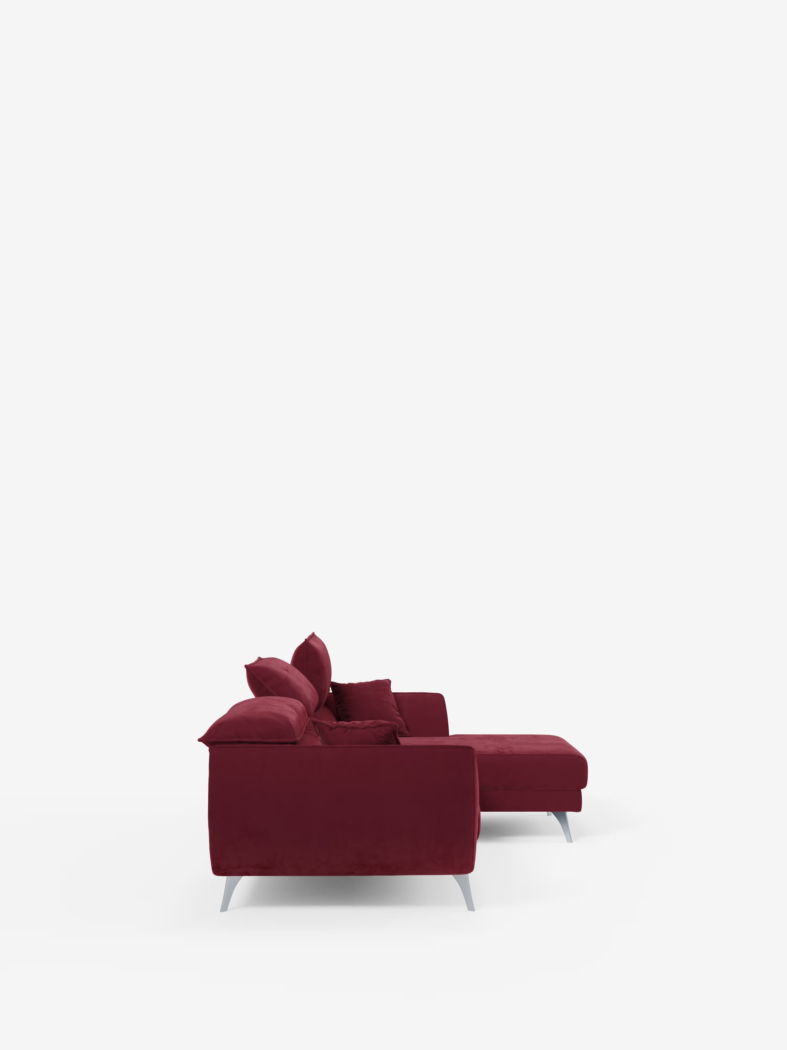 Una vista laterale del divano angolare con penisola e sedute estensibili “Michelangelo” di Divani.Store ne mette in risalto il design moderno, realizzato in tessuto T30 effetto velluto rosso intenso e resistente alle macchie. Il divano è dotato di tre cuscini di seduta, cuscini coordinati, eleganti gambe in metallo, braccioli bassi, una chaise longue integrata per un maggiore comfort e versatilità e poggiatesta reclinabili, il tutto su uno sfondo bianco a tinta unita.