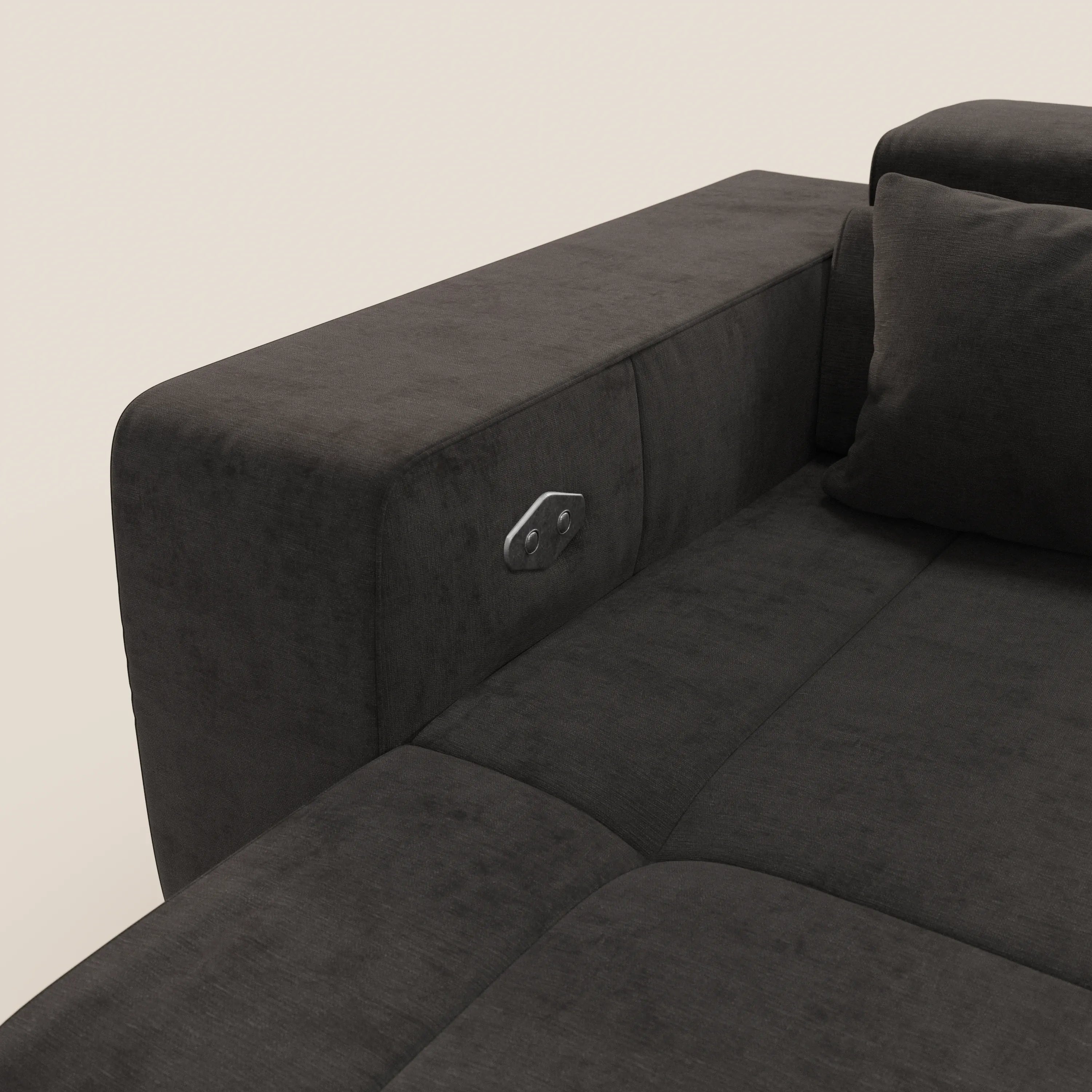 Primo piano del Monarch Divano angolare di Divani.Store in tessuto T31 grigio scuro, dotato di Relax Elettrico con pulsantiera in metallo sul bracciolo sinistro. I poggiatesta reclinabili e parte del cuscino sono visibili su uno sfondo chiaro.